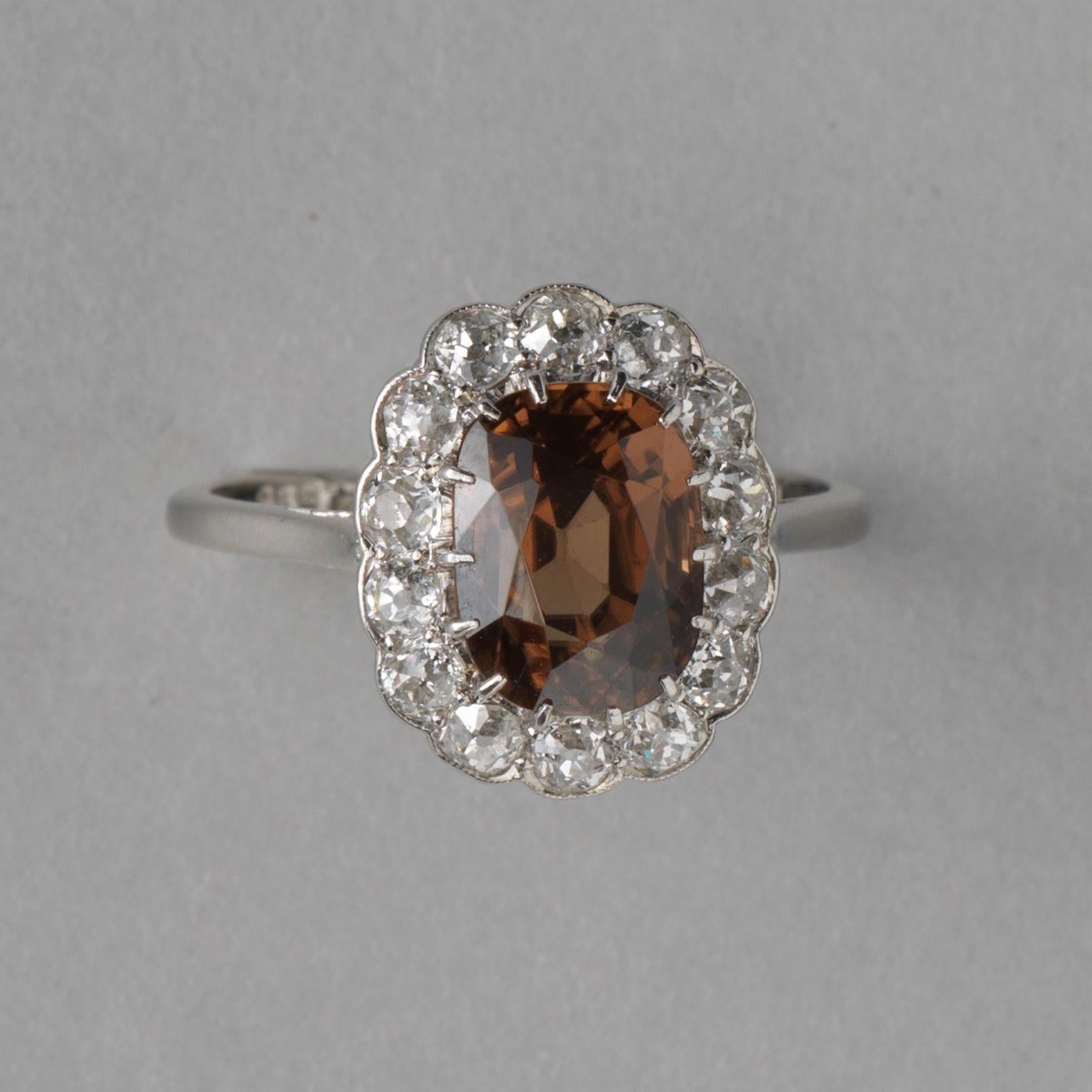 A platinum Edwardian cluster ring set with a brown oval facetted zircon (app. 2.27 carat) surrounded by old cut diamonds (app. 0.89 carat), numbered: U4598, England, circa 1910.

ring size: 18.5 mm / 8.5 US.
weight: 5.22 grams
dimensions zircon: 10