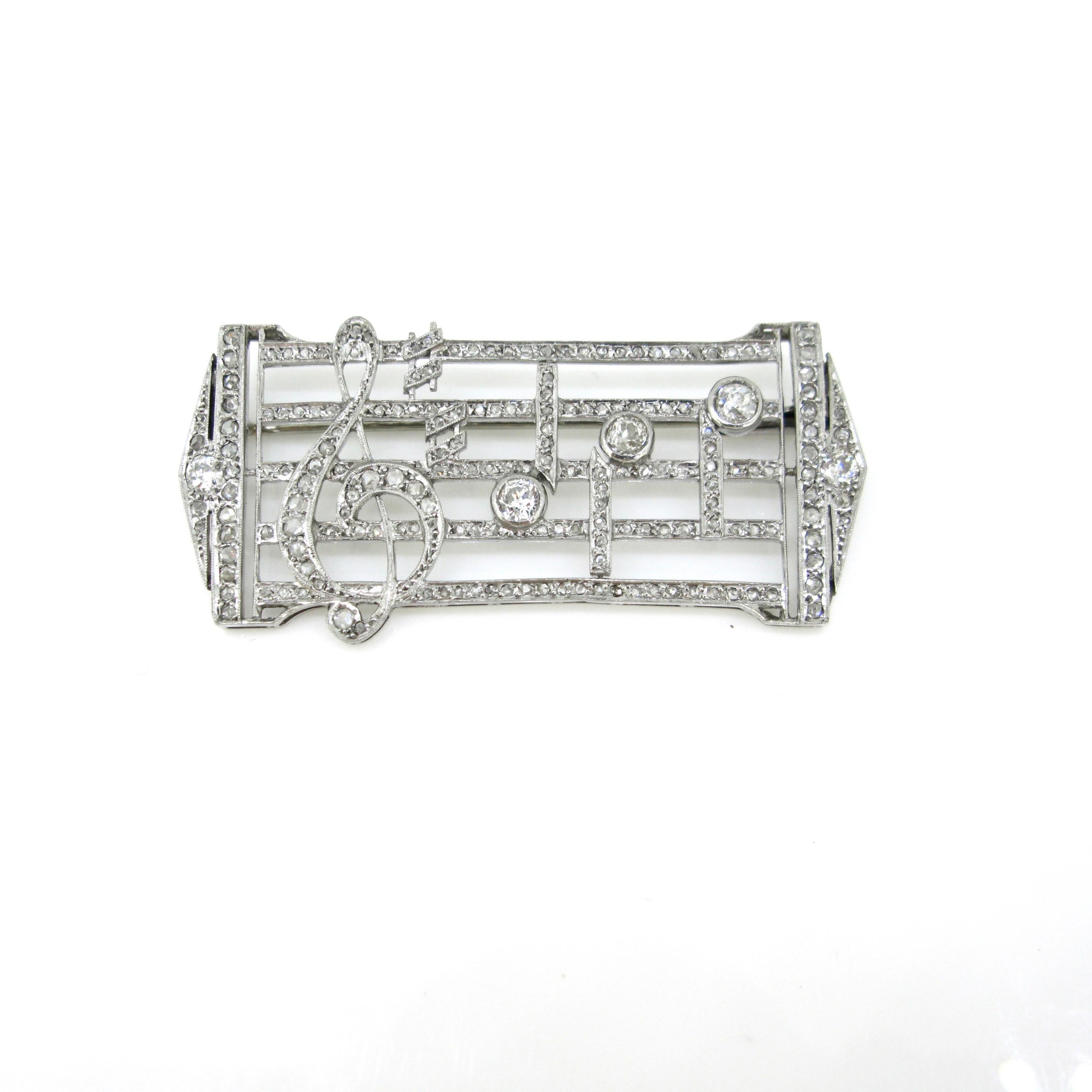 This brooch features a music score with the treble clef, 2 hashes and 3 notes. It was made in platinum and adorned with old mine cut diamonds and rose cut (colour: I/J – clarity: VS/SI) There is an approximate total carat weight of 0.70ct for the 5