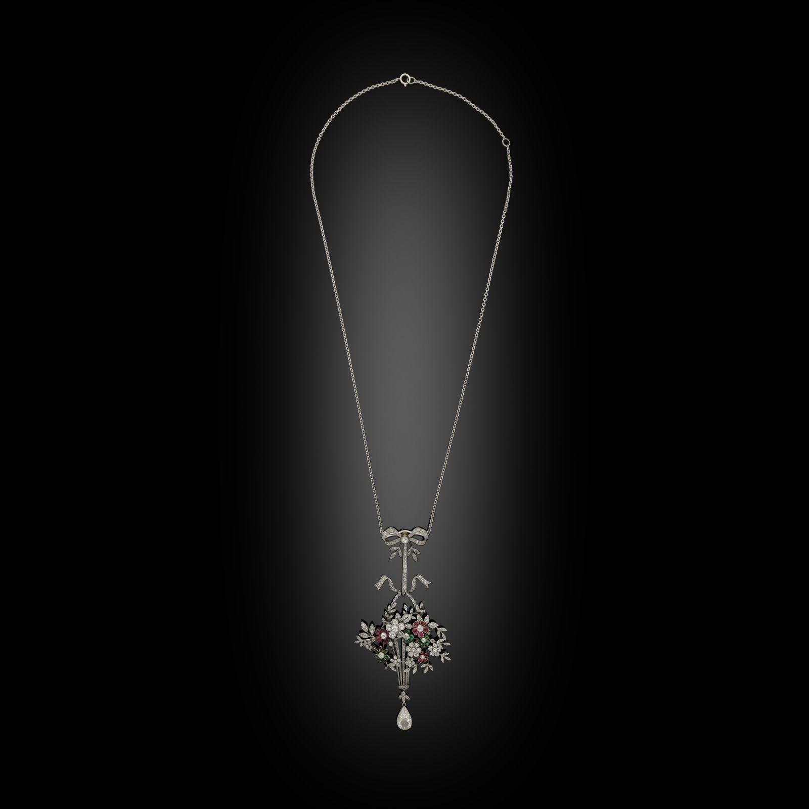 A beautiful platinum and multi-gem set giardinetto pendant c.1910, the pendant designed as a long tapering openwork basket with rope twist handle finely crafted in platinum and set throughout with old-cut diamonds, filled with a generous bouquet of