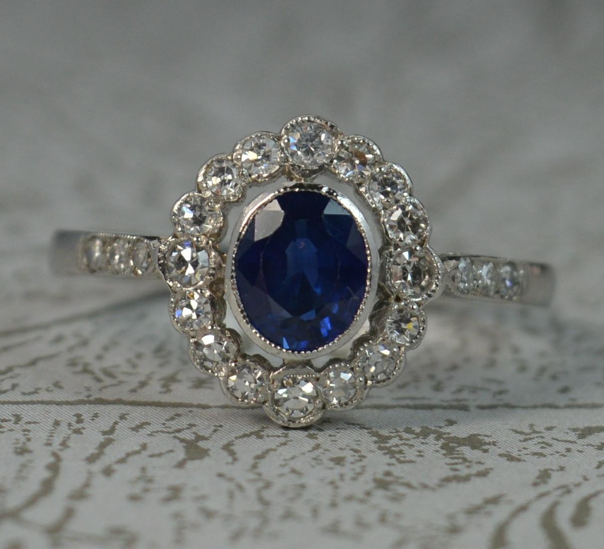 A superb Edwardian era design, contemporary cluster ring.
Solid platinum throughout. Designed with a single oval cut sapphire to the centre 5mm x 6.3mm approx. Surrounding are sixteen round eight cut diamonds in bezel settings with further diamonds