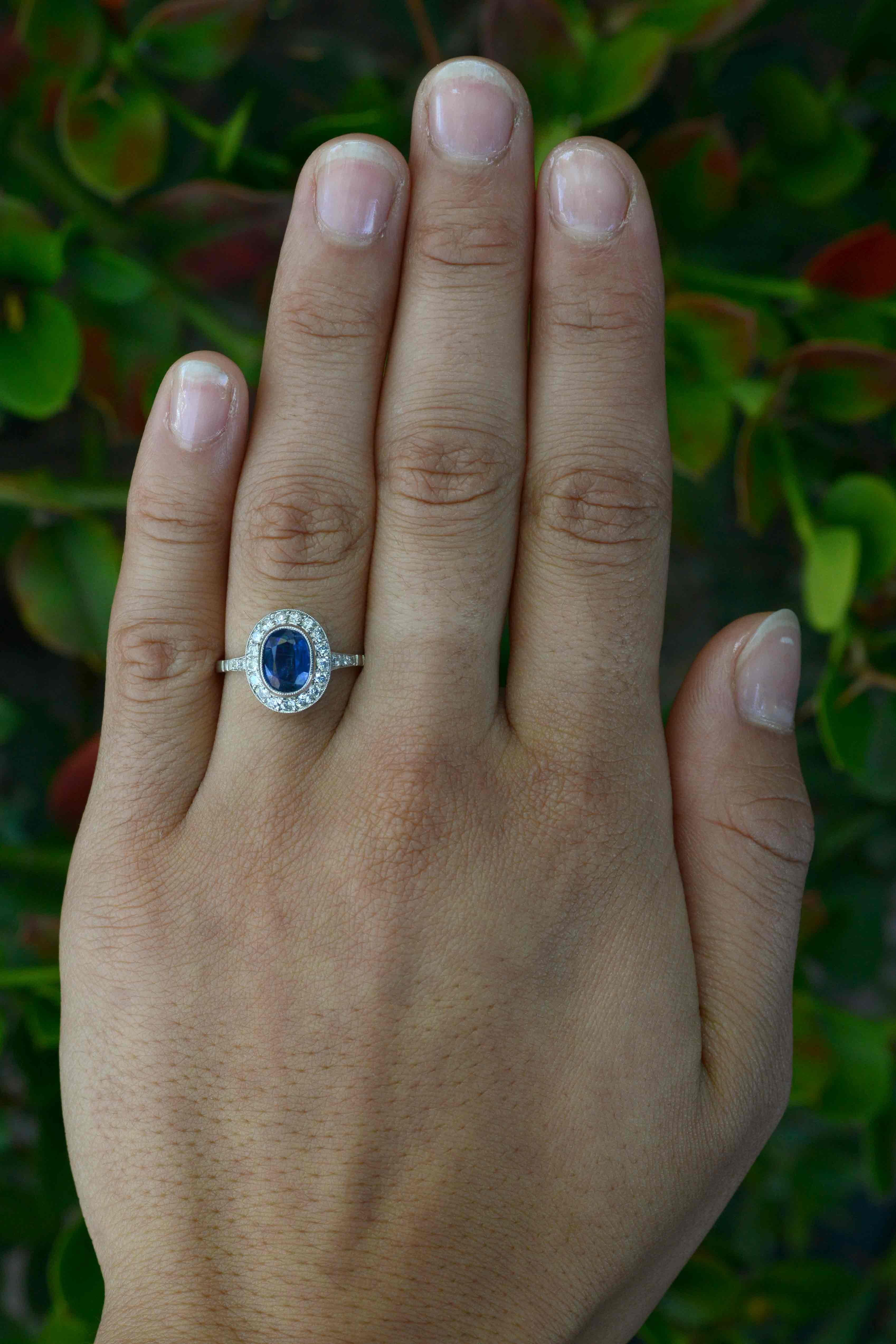 A revivalist Edwardian sapphire engagement ring adorned with a sparkling diamond halo. The finger coverage on this unusual, elongated oval ring is breathtaking. Weighing an impressive 1.87 carats, the captivating natural sapphire of a vivid,