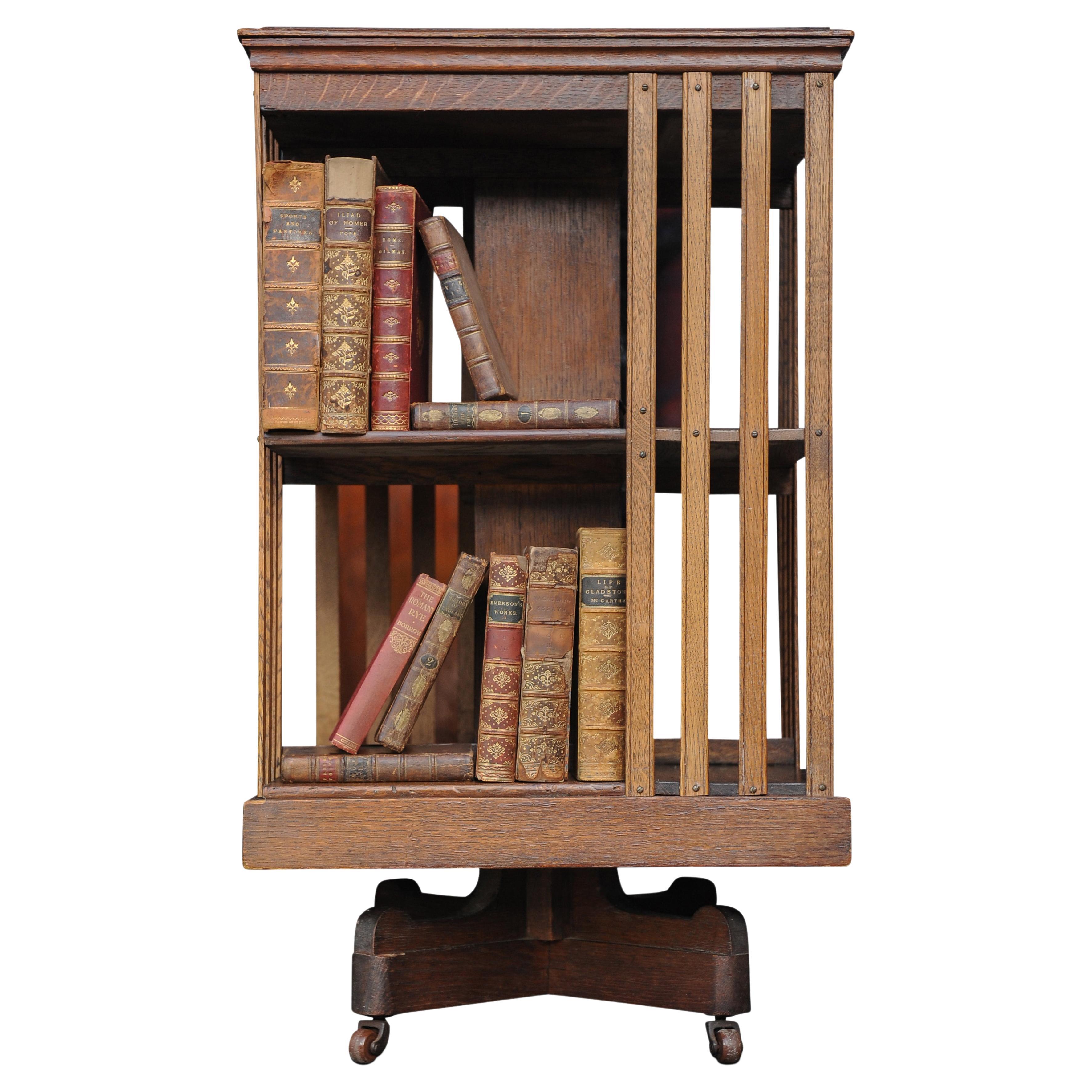 An Elegant Edwardian Revolving Two Tier Oak Library Bookcase With Slatted Sections & A Graduated Top Set On A Revolving Ebonised Base With Porcelain Castors 

Extra dimensions 
Shelf depth 15cm
Shelf width 29cm 
Shelf height top 25cm

Shelf height