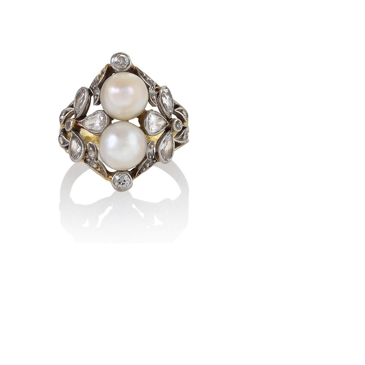 An Edwardian ring featuring two pearls and 22 diamonds set in platinum, with an 18 karat gold shank. The two pearls, which stack up the finger, are elegantly framed by a naturalistic motif echoing the form of a clover made of pear-cut diamonds. The