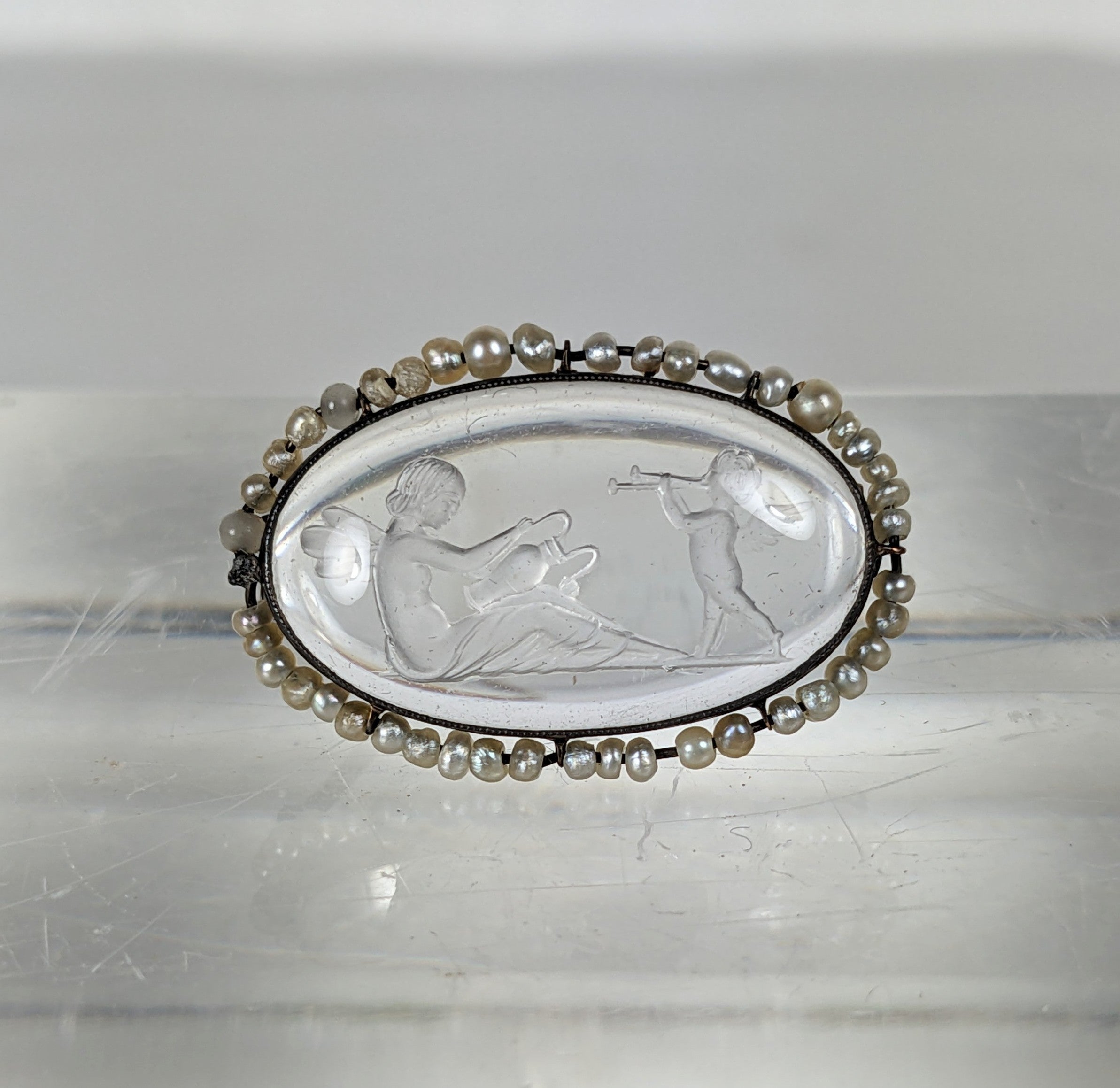 Petite mais charmante broche édouardienne en cristal de roche et perles de rocaille du début des années 1900. Serti en or 14k. Intaille sculptée à la main d'un chérubin chantant la sérénade à un personnage assis ressemblant à une fée. Des perles de