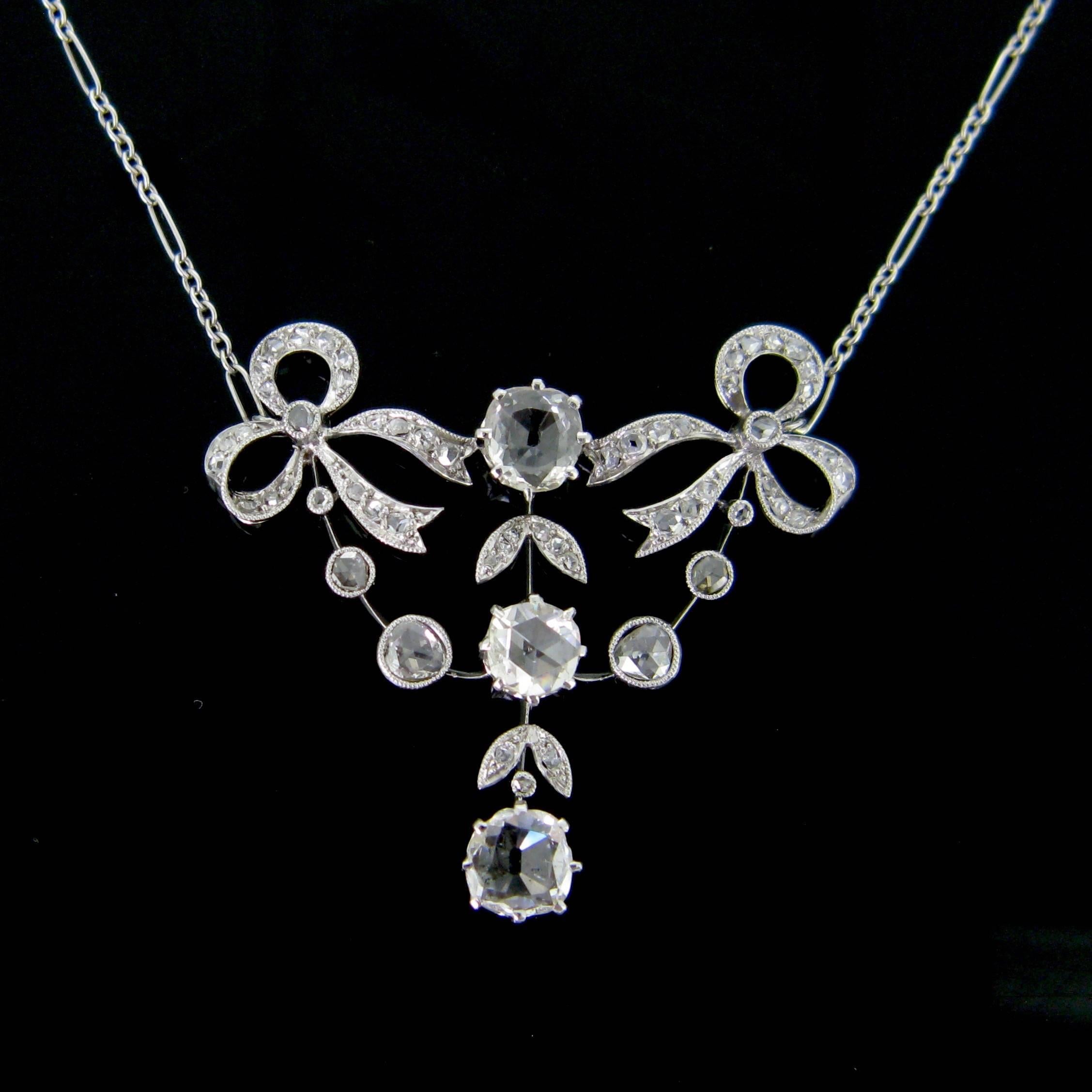 This ravishing necklace is a real testimony of the Edwardian period. It features a platinum pendant adorned with 2 ribbons and garland. It set with a rose cut diamond in its center, with 2 table cut diamonds and rose cut diamonds. The dangling
