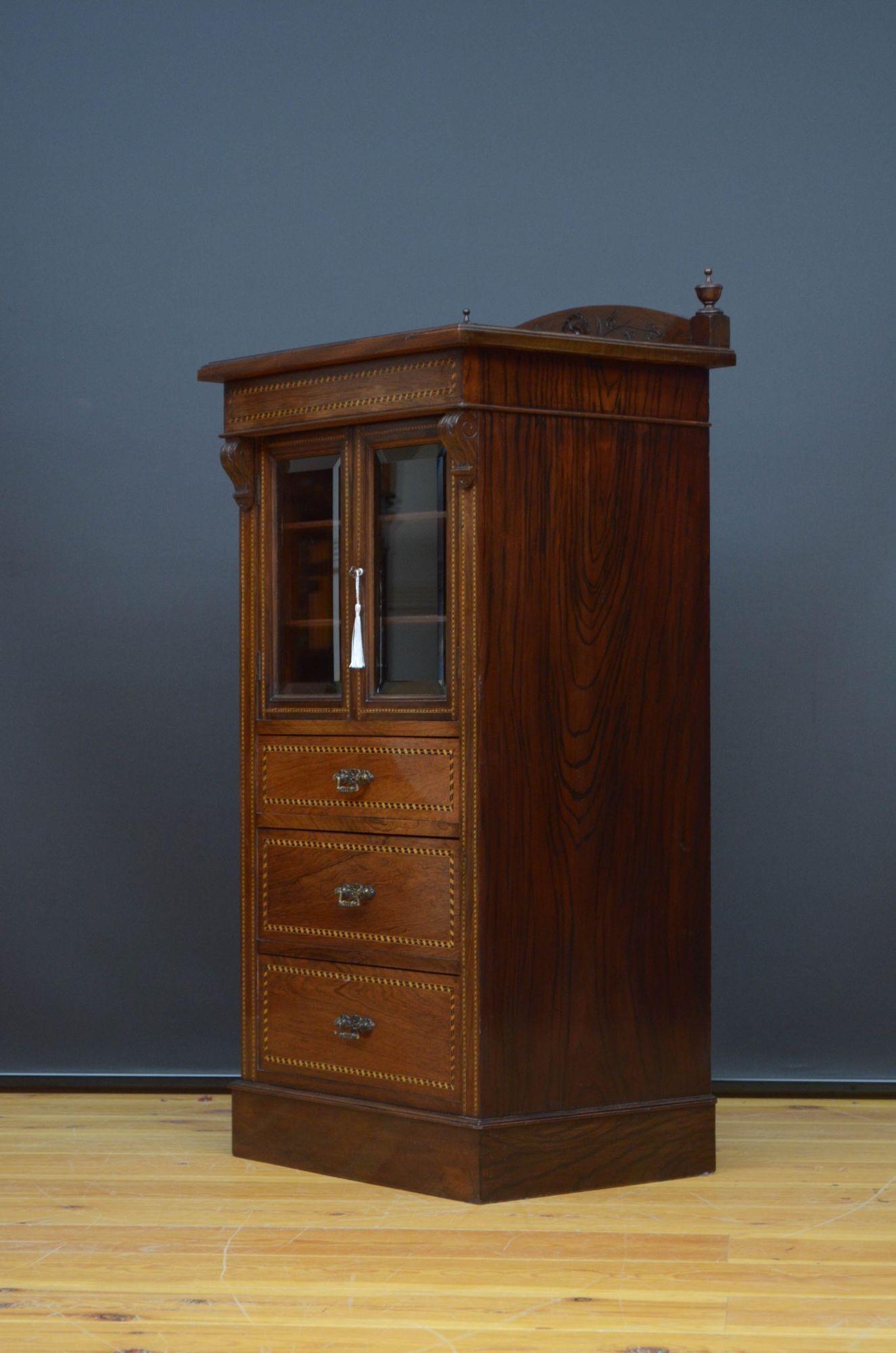 St028 Elegant Edwardian rosewood music cabinet with simulated rosewood mahogany sides, having shaped upstand with finials to the back edge and moulded top above a paid of glazed doors with original bevelled edge glass and working lock and a key
