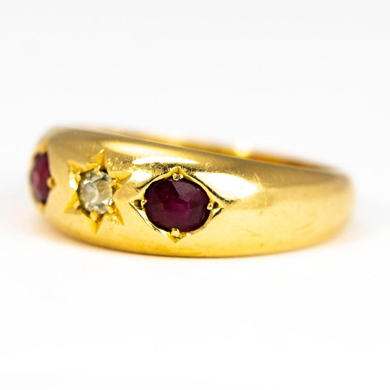 The central diamond in this glossy 18ct gold band measures 10pts and is set in a star setting. The rubies that sit either side of this stone measure 20pts and are held in flush claw settings. 

Ring Size: Q 1/2 or 8 1/2 
Band Width: 7.5mm 

Weight:
