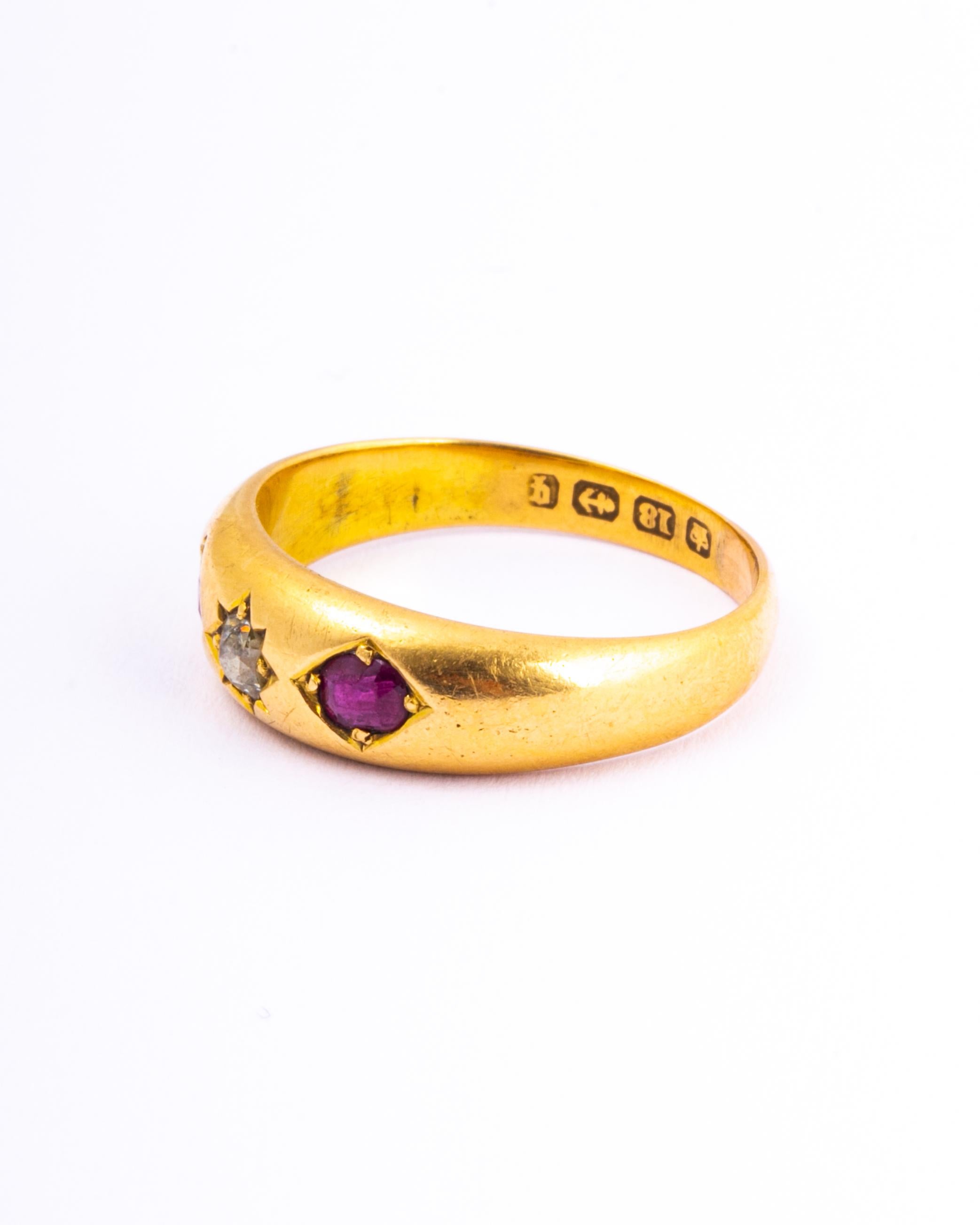 The central diamond in this glossy 18ct gold band measures 10pts and is set in a star setting. The rubies that sit either side of this stone measure 15pts and are held in flush claw settings. 

Ring Size: Q or 8 1/4
Band Width: 6mm 

Weight: 3.7g 