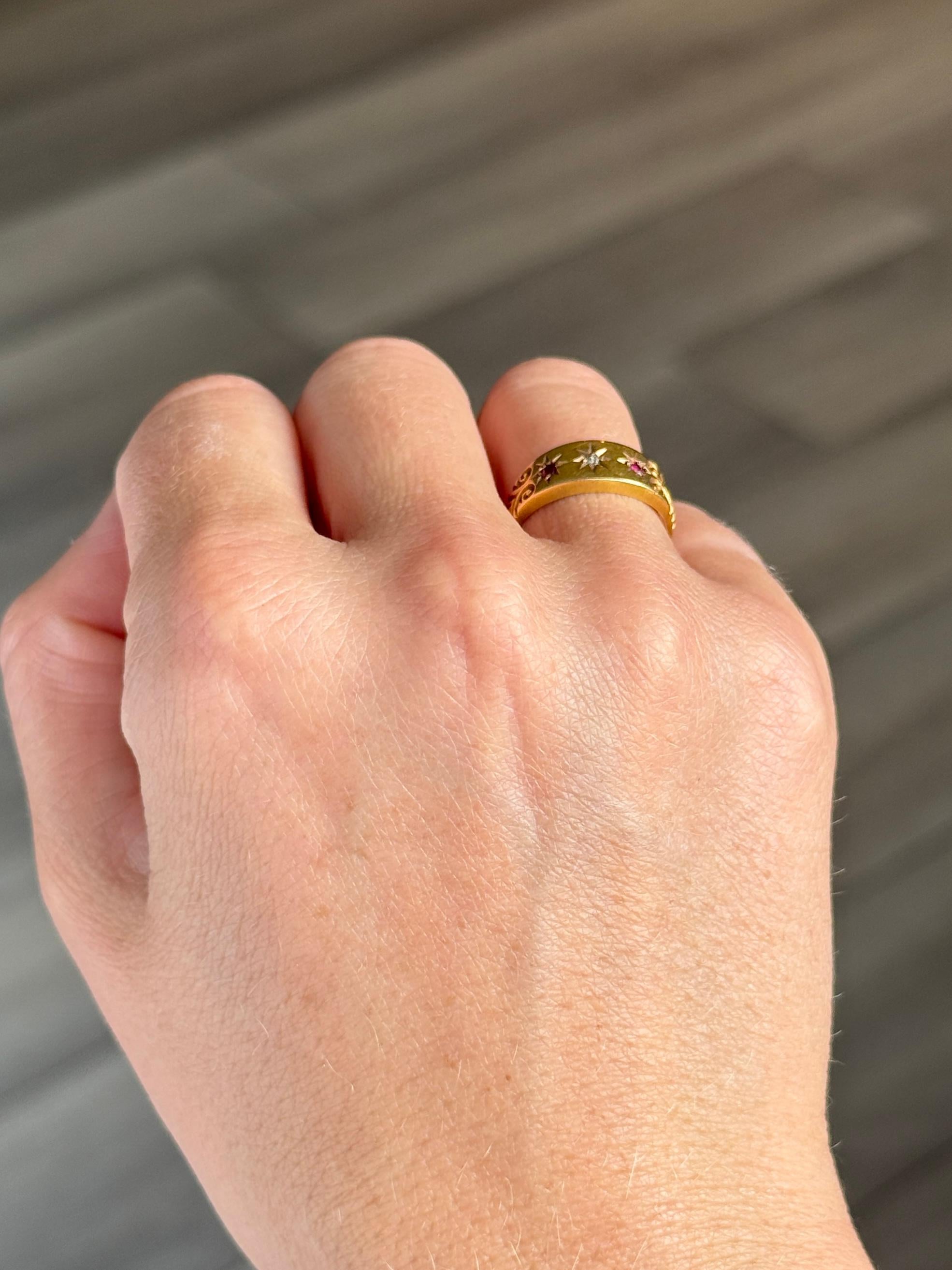 The central rose cut diamond in this glossy 18ct gold band measures 2pts. The rubies that sit either side of this stone measure 4pts each. Hallmarked Birmingham 1900.

Ring Size: J 1/2 or 5 
Band Width: 7mm 

Weight: 2.1g 