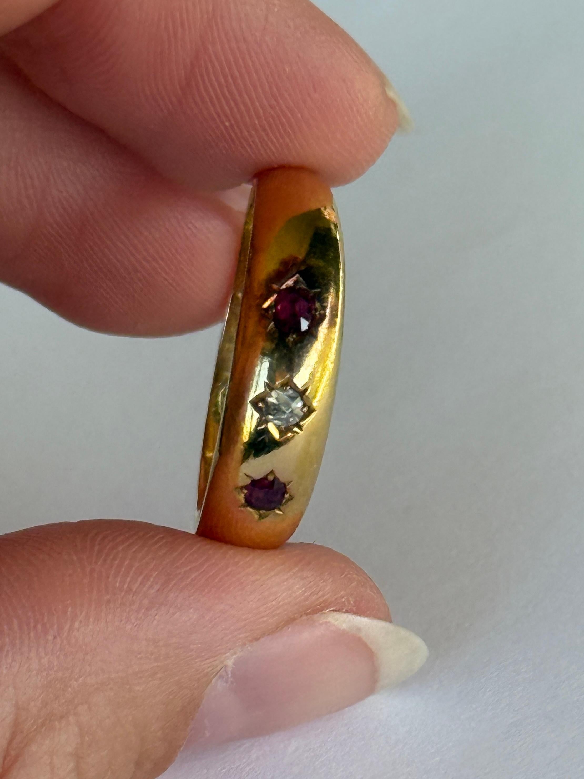 The central rose cut diamond in this glossy 18ct gold band measures 7pts. The rubies that sit either side of this stone measure 5pts each. 

Ring Size: T or 9 1/2 
Band Width: 6mm 

Weight: 2.8g 