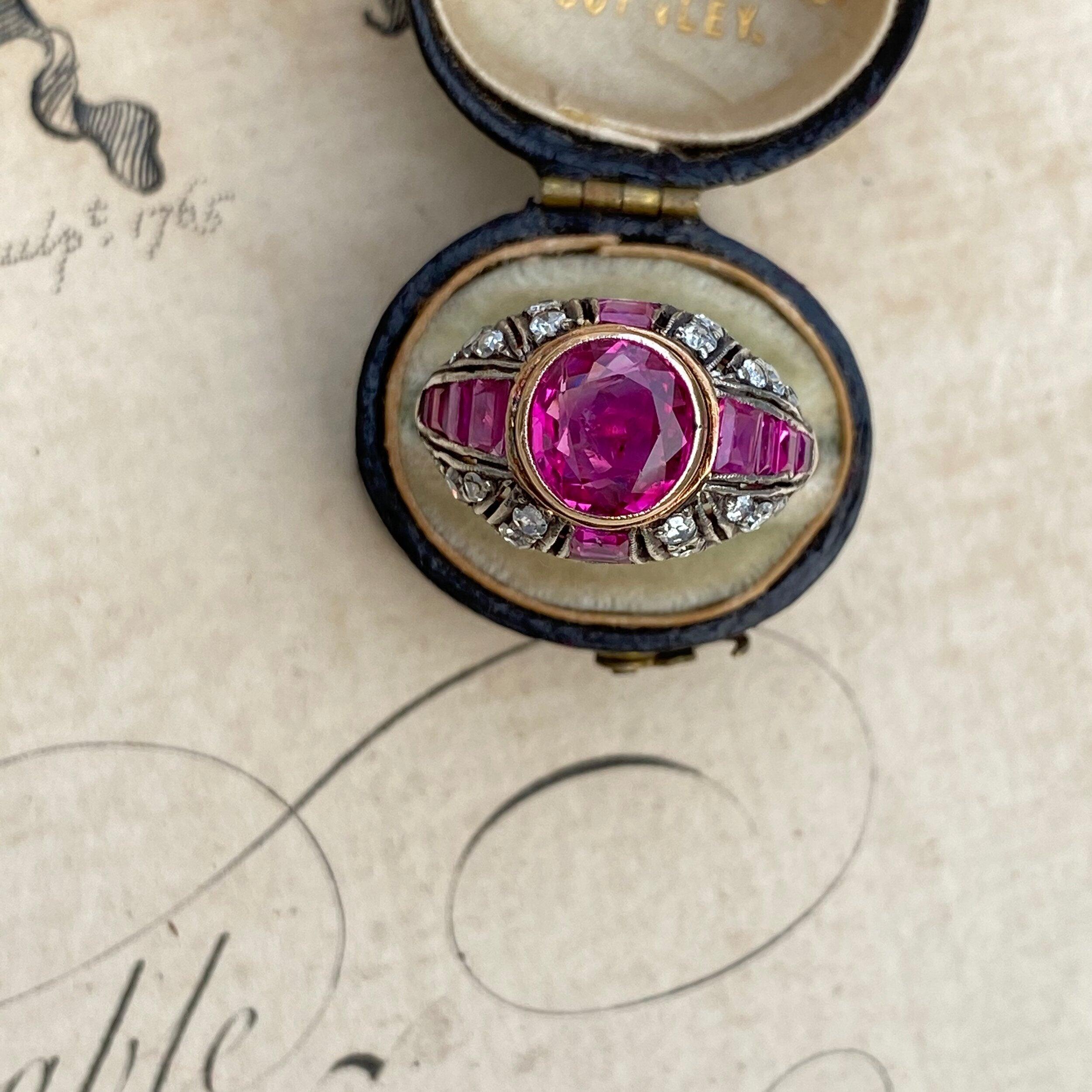 Crowned with a crystalline magenta red ruby, this lovely Edwardian bombe style ring boasts four rows of richly saturated calibre rubies divided by twinkling single cut diamonds that taper down the gently domed setting. Expertly fabricated in 14k
