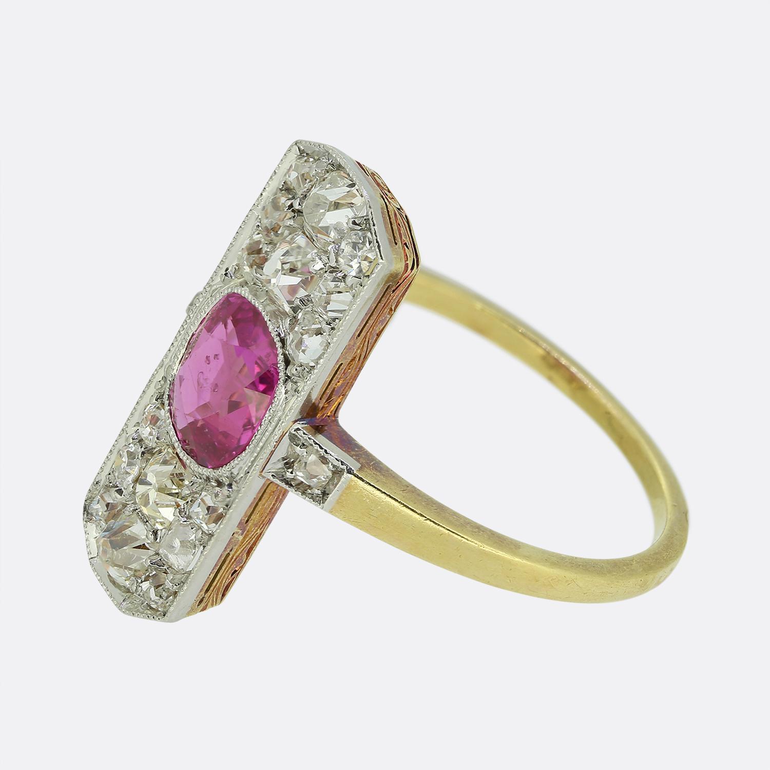 Aquí tenemos un anillo de racimo eduardiano. La cara de este anillo presenta un rubí rojo centralizado con un ligero matiz rosado, rodeado de diamantes redondos facetados de talla antigua. El engaste rectangular alargado está elaborado en platino,