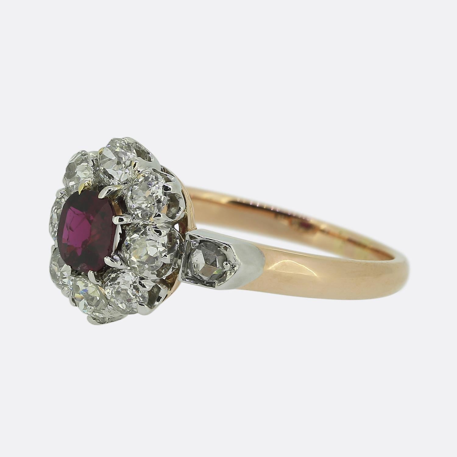 Here we have an elegant Edwardian cluster ring featuring a captivating red ruby at its centre. This principal stone is surrounded by a halo of bright white round faceted old cut diamonds, each meticulously set to enhance the centre stone's allure.