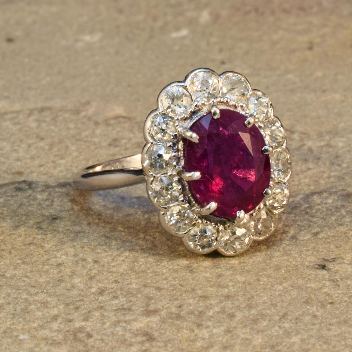 A classic Edwardian cluster ring, handmade with quality craftsmanship. It has been modelled in Platinum and 18ct White Gold with markings on the inner band (faded). The design features an oval cut 0.80ct Ruby in the centre with a claw setting and a