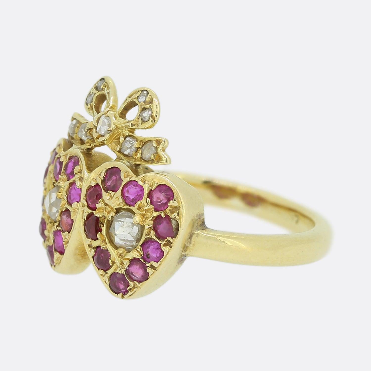 Dieser Ring aus 18 Karat Gelbgold stammt aus der Edwardianischen Ära. Die Mitte jedes Herzens ist mit einem Diamanten im Rosenschliff besetzt, der von roten Rubinen umrahmt wird. Oberhalb der Herzen befindet sich eine diamantbesetzte