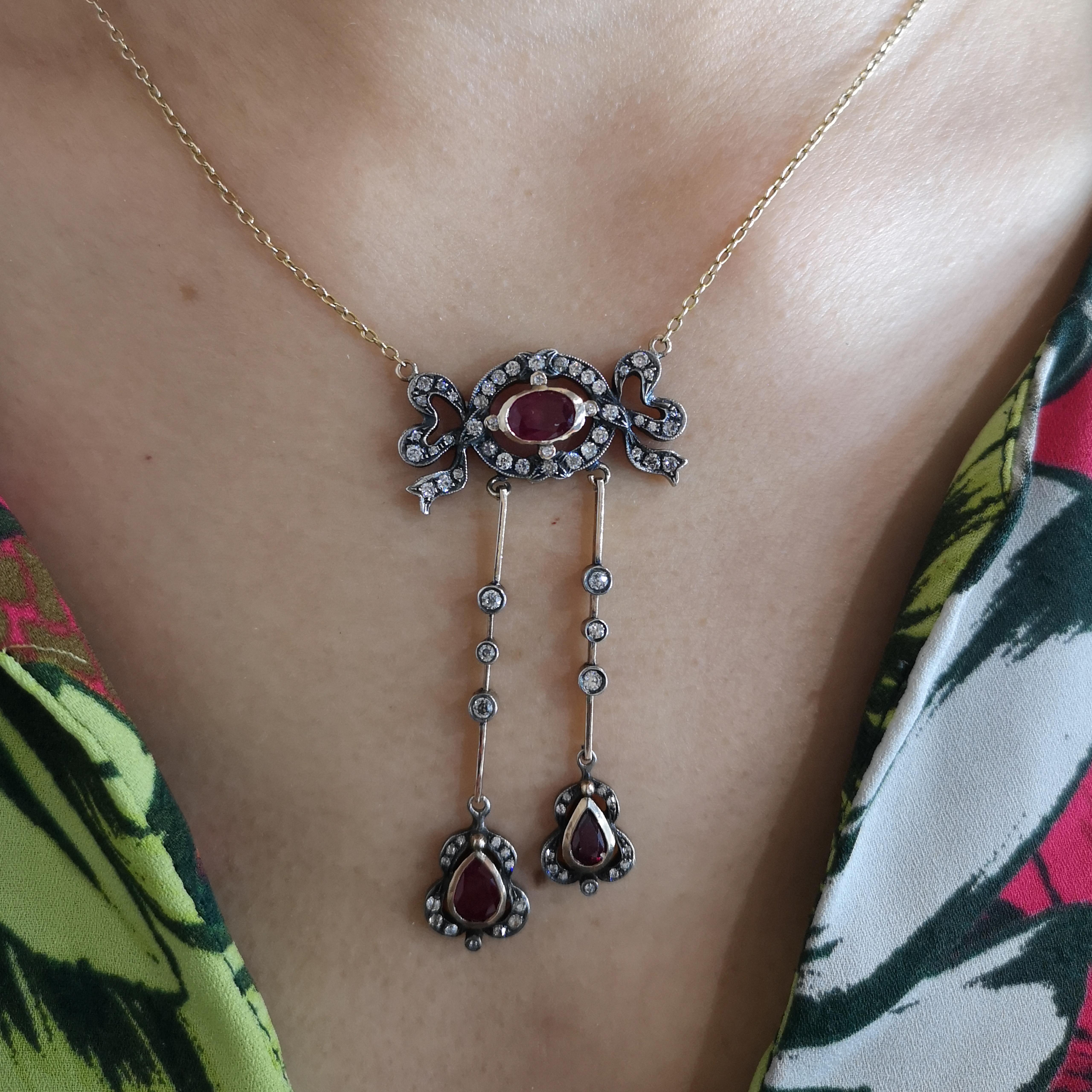 An Edwardian ruby and diamond négligée pendant, with an oval faceted ruby, in the centre of an old-cut diamond surround, in the form of a bow, suspending two drops, set with a pear shape faceted rubies and old-cut diamonds, on a later gold