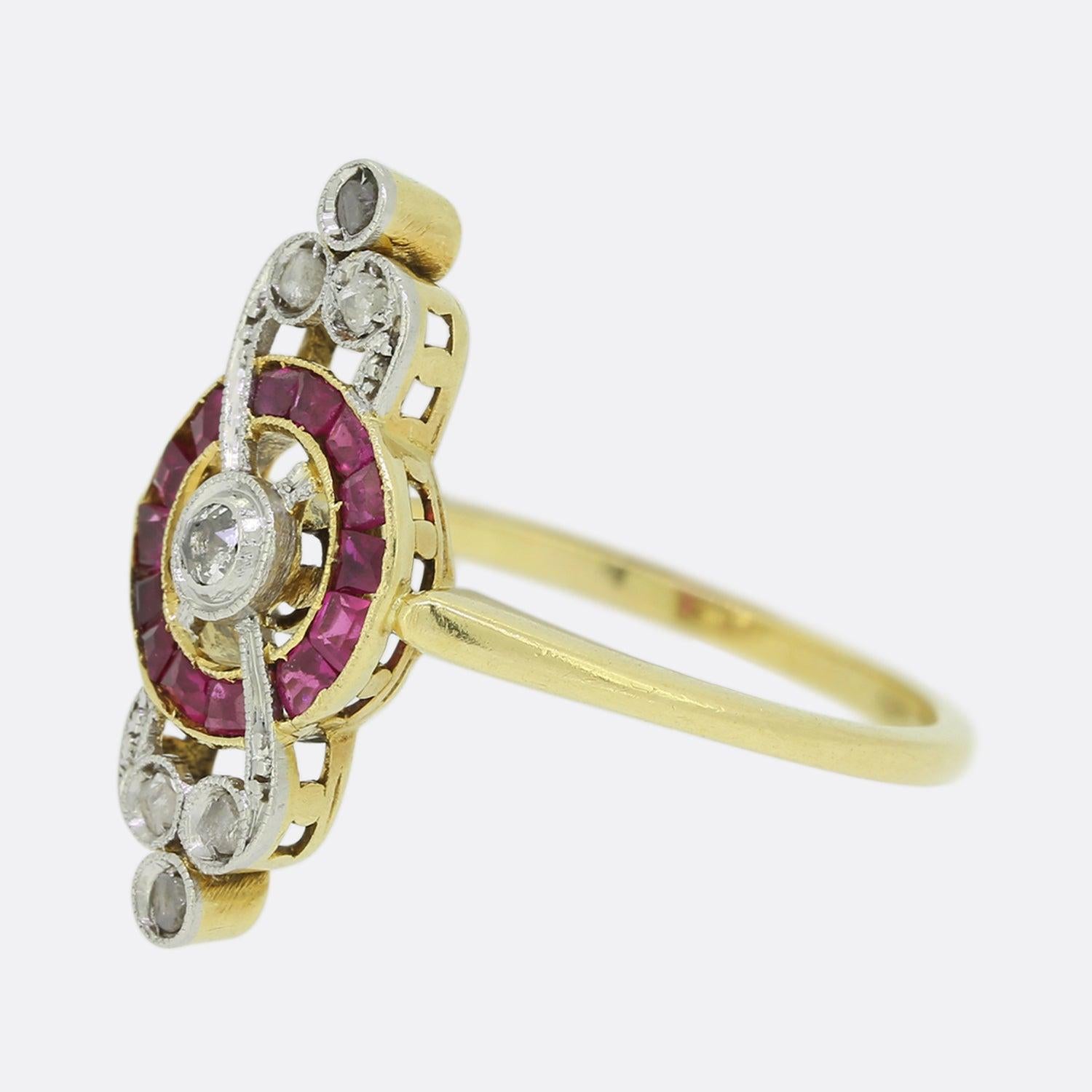 This is an Edwardian 18ct yellow gold ruby and diamond ring. The ring features a target centre with a single old cut diamond surrounded by 14 calibrated rubies. Above and below the centre there are 3 sparkling rose cut diamonds. The ring has a free