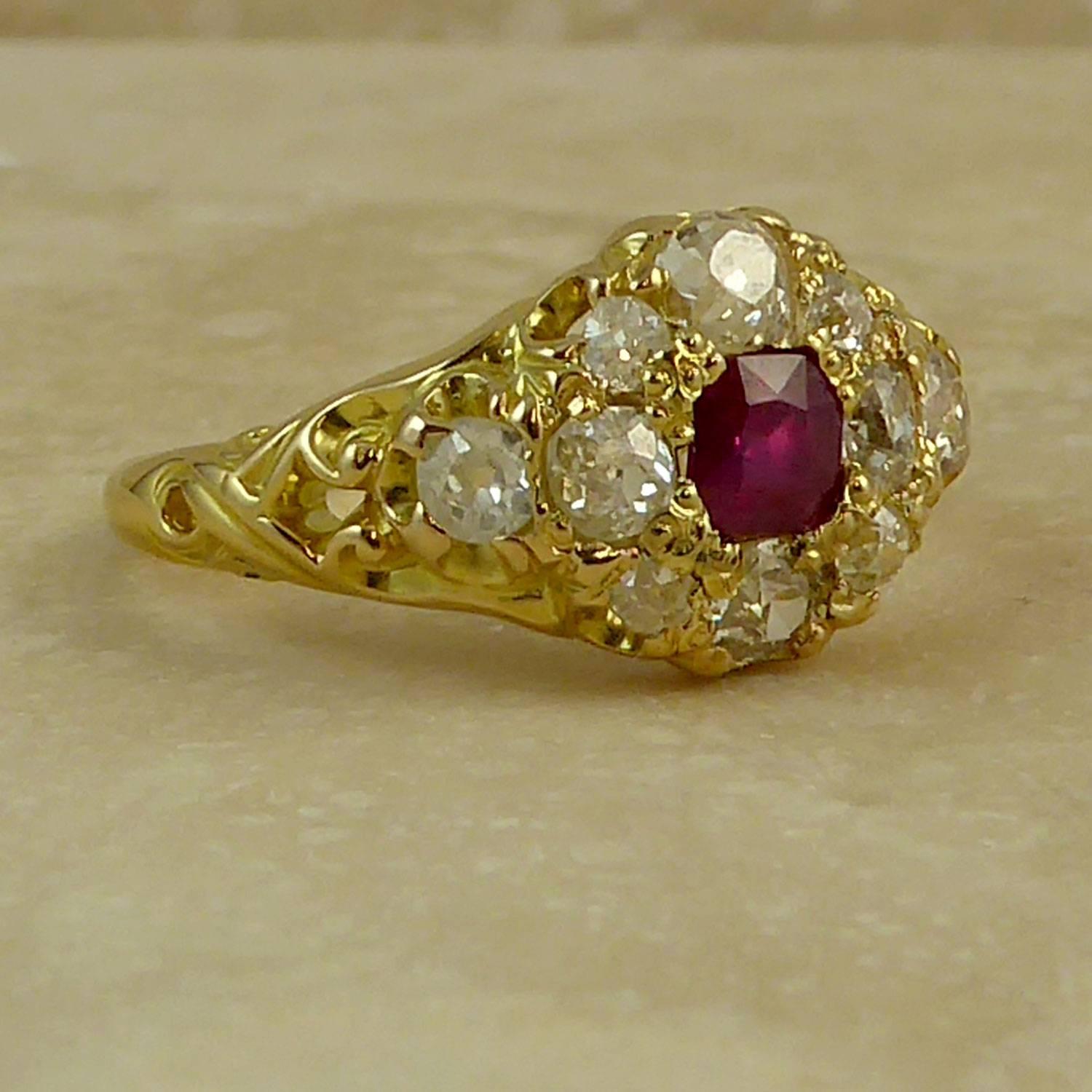 An Edwardian ruby and diamond cluster ring set to the centre with an octagonal cushion, cushion shaped, Swiss-cut ruby of slightly purple mid-red colouor, measuring approx. 4.4mm x 4.2mm x 2.06mm and with a weight of approx. 0.36ct.  The ruby is in