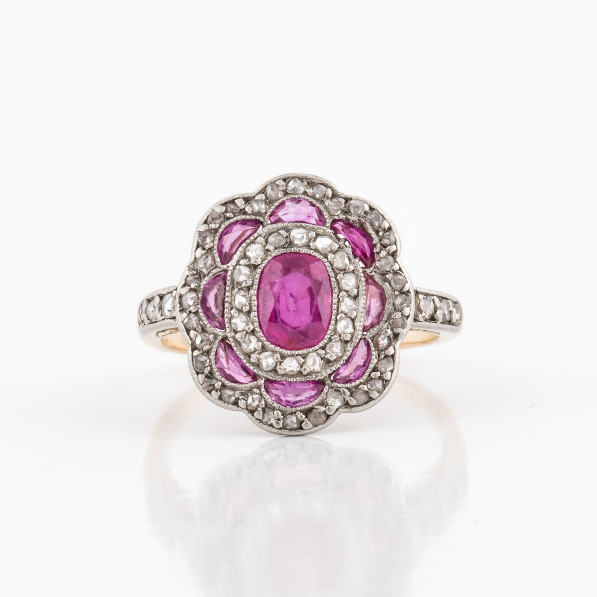 Edwardian ring composed of 18K yellow gold and platinum featuring rubies accented by diamonds.  There is one cushion cut ruby that totals 0.60 carats, with eight half-moon rubies that total 0.36 carats.  Additionally there are 54 round single-cut