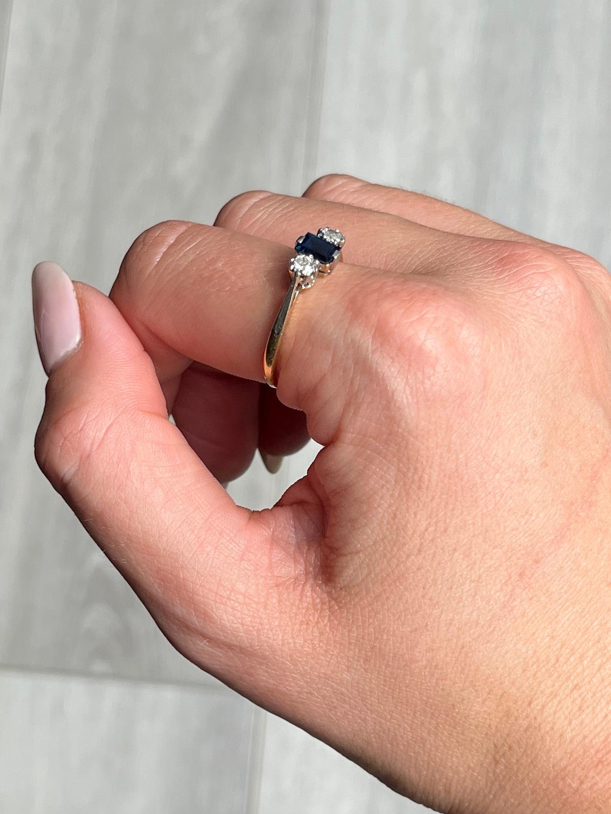 This stunning 18ct gold and platinum ring holds a central emerald cut sapphire approximately 50pts in size and is of good blue colour. Two old cut diamonds are set either side of the centre stone each measuring approximately 10pts each. 

Ring Size: