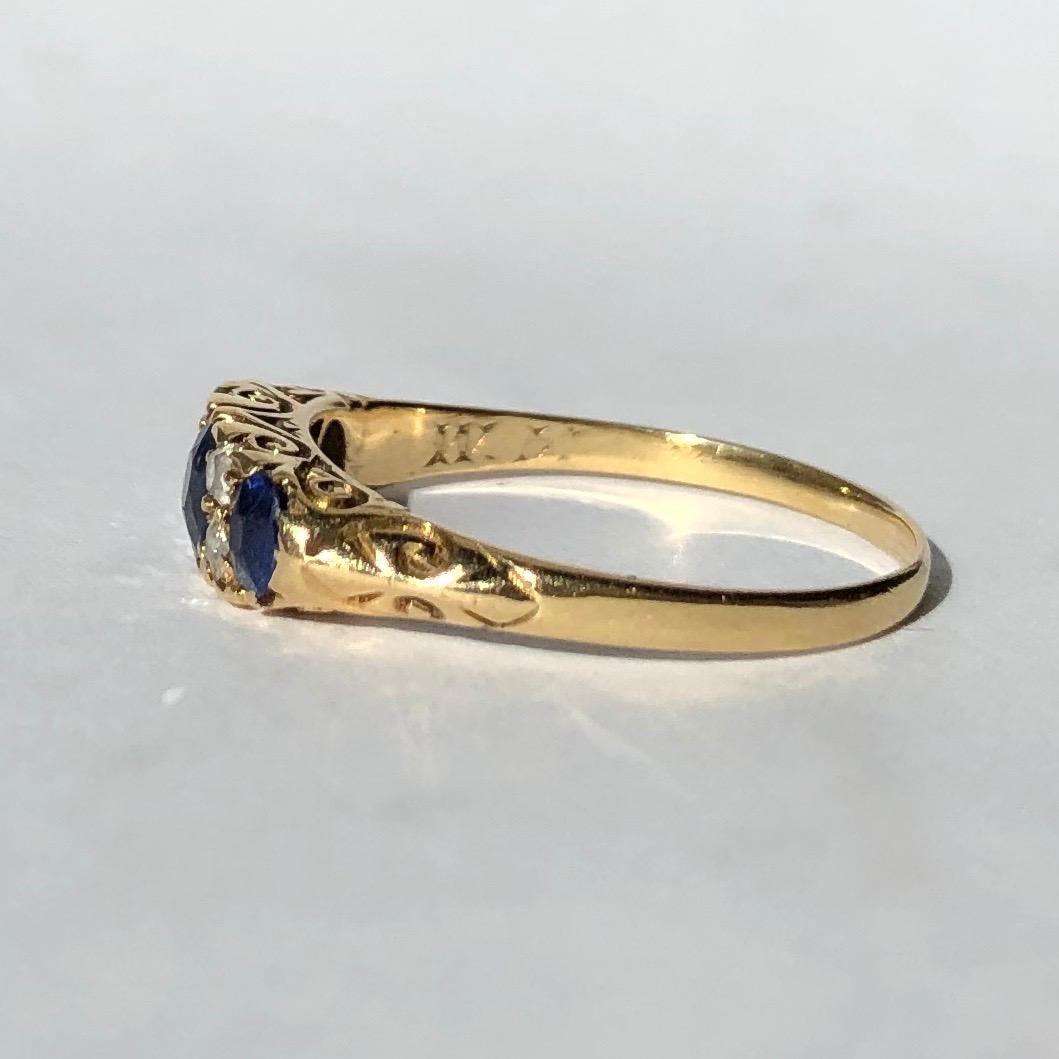 The sapphires in this ring total 70pts and are a gorgeous bright blue colour. Either side of the largest stone in the centre are pairs of old cut diamonds. The stones are all set in 18carat gold and the gallery is made up of scroll detail. There is