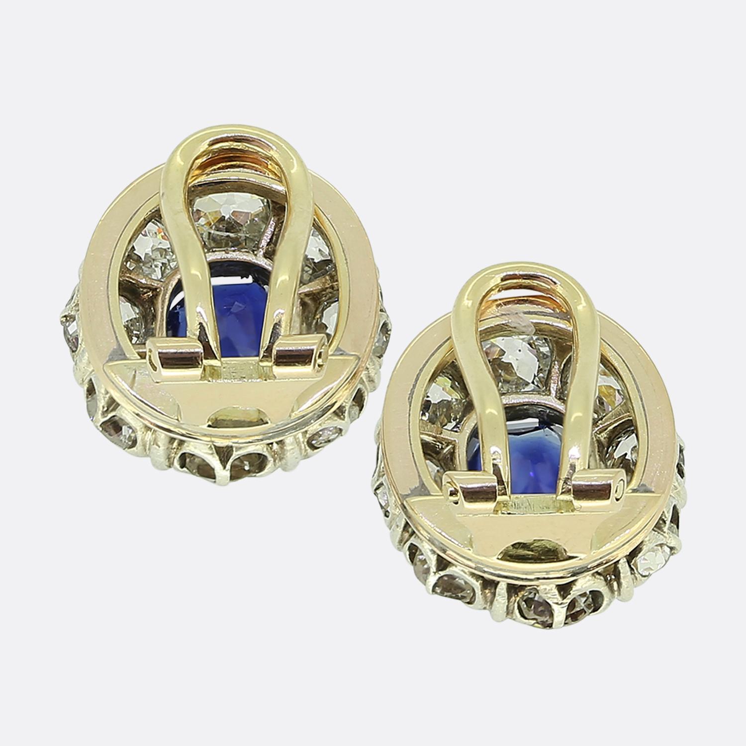 Nous avons ici une charmante paire de boucles d'oreilles de style édouardien. Réalisée en or jaune 18ct et en platine, chaque boucle d'oreille est ornée d'un saphir bleu ovale au centre, entouré d'un halo de diamants blancs ronds à facettes taillés