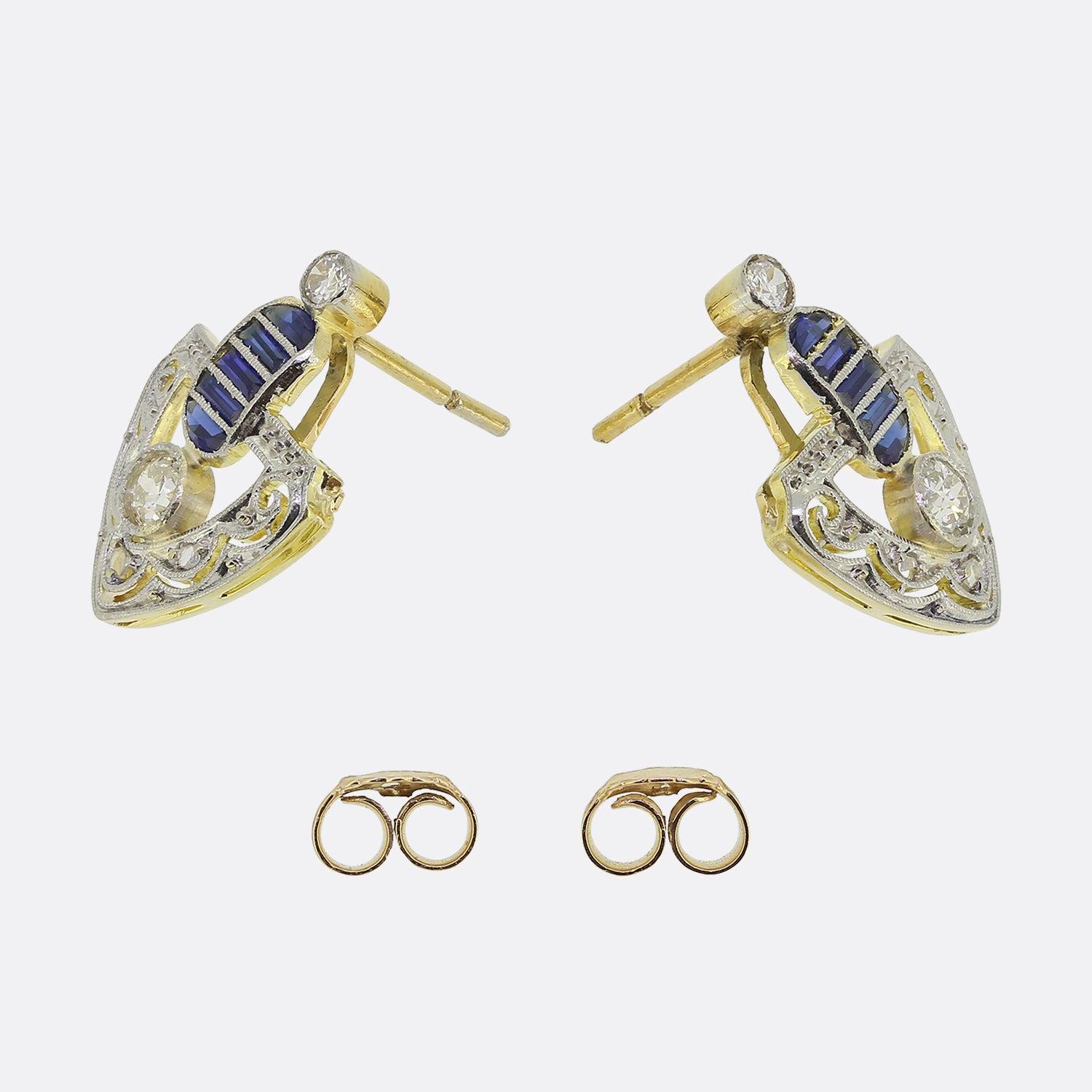 Here we have a beautifully detailed pair of sapphire and diamond drop earrings from the Edwardian era. Each piece showcases an open framework with an intricately detailed beaded pattern. This ornate design compliments the centralised round diamond