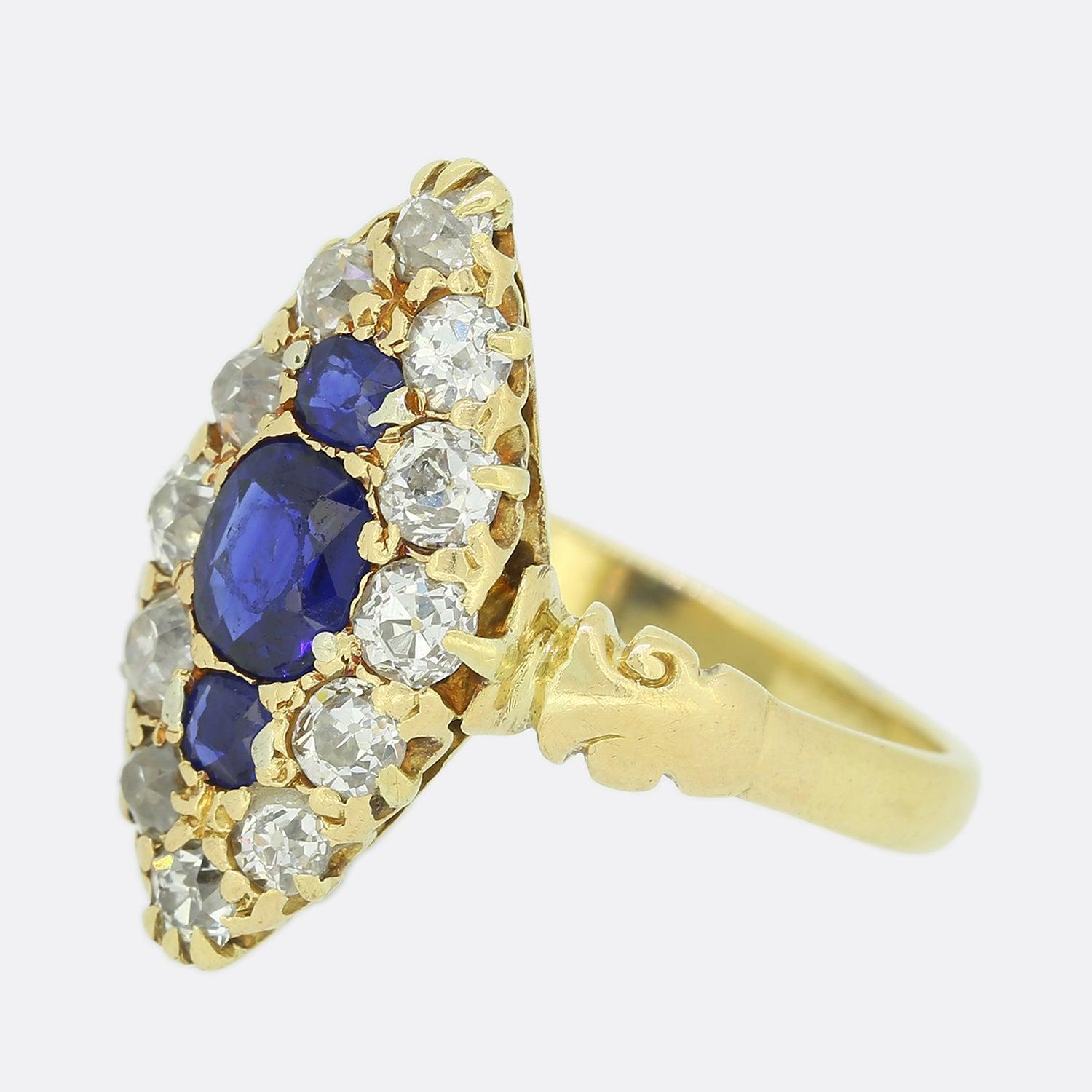 This is an exceptional antique navette ring. Crafted in 18ct yellow gold, the ring boasts a centralised oval shaped sapphire with a single neighbouring round sapphire sitting atop and below. The surrounding old cuts diamonds create a gorgeous