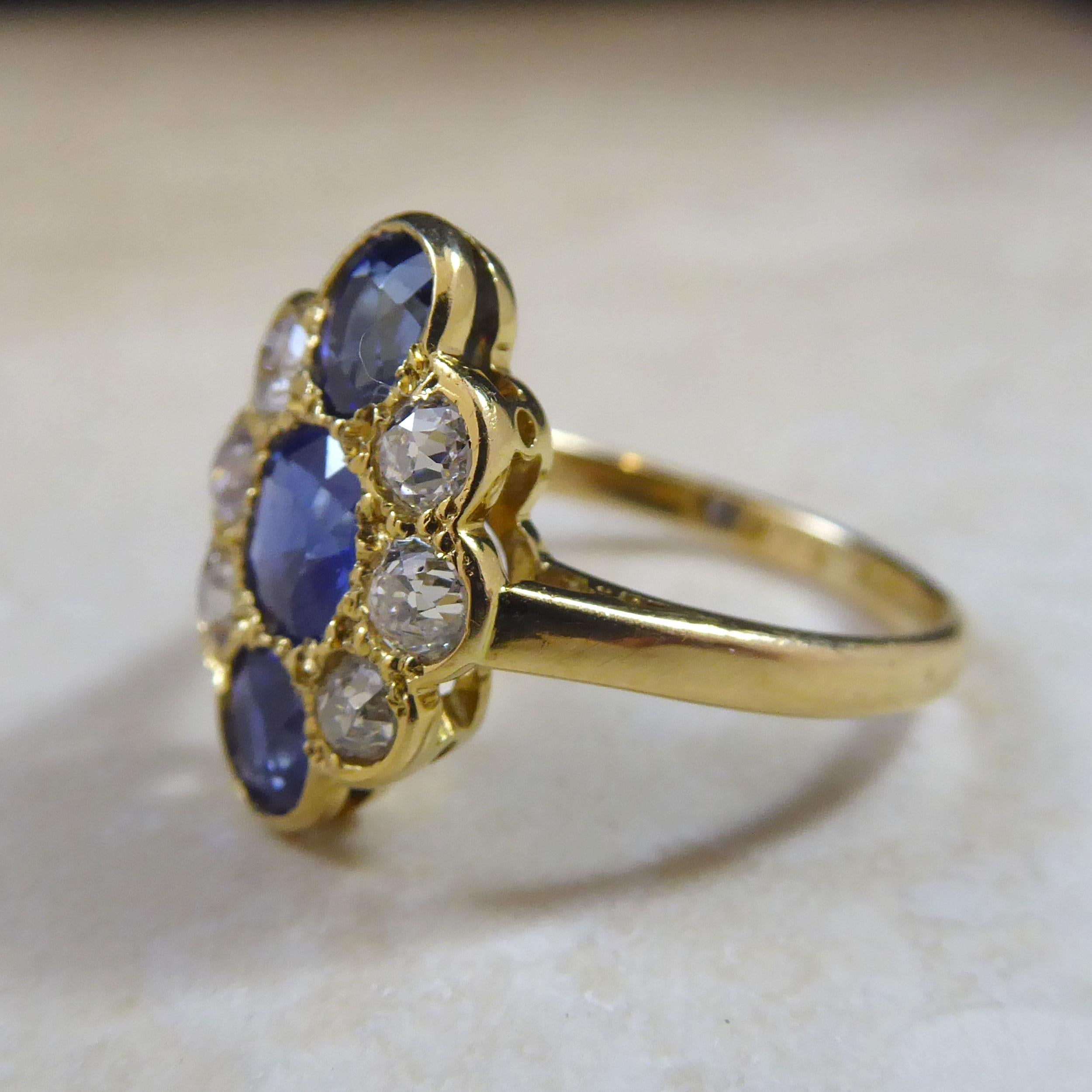 An Edwardian era sapphire and diamond oval cluster ring set with three oval, mixed-cut, medium blue sapphire arranged in a row down the finger.  To each side three old Europan Cut Diamonds.  The gemstones are all held in rub over and beaded settings