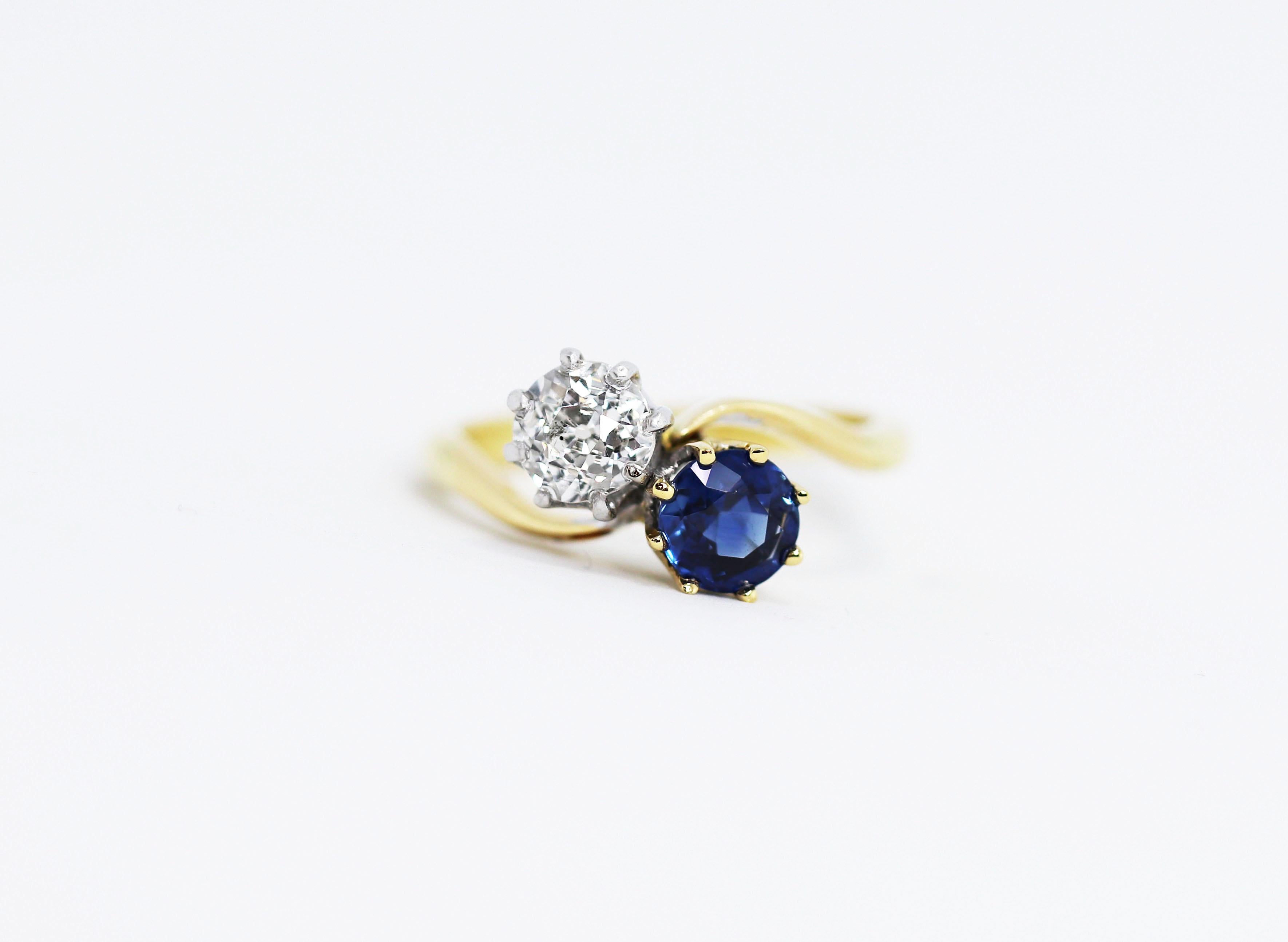 Beautiful Edwardian two-stone twist ring set with a natural blue sapphire weighing 0.87 carat and an old mine cut diamond weighing 0.75 carat. The diamond is set in a platinum 8 claw crown collet with the blue sapphire set in a 18 carat yellow gold
