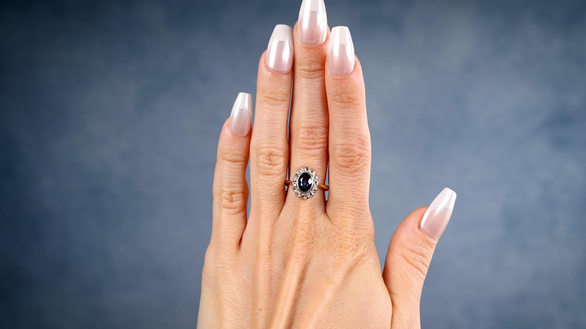 Ein Edwardian Sapphire Diamond 18k Gelbgold Platin Ring. Mit einem ovalen Saphir im Mischschliff mit einem Gewicht von etwa 1.50 Karat. Akzentuiert durch 12 Diamanten im Rosenschliff mit einem Gesamtgewicht von etwa 0,50 Karat, eingestuft als nahezu
