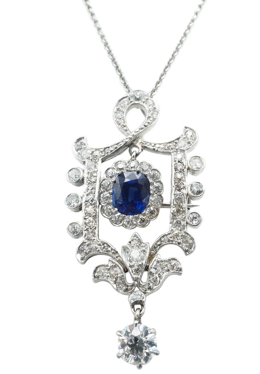 Réalisée en platine, elle est ornée d'un saphir rectangulaire de taille coussin et d'un diamant de taille ancienne, entourés de taille ancienne, de taille suisse et de taille unique.  La chaîne est en or blanc 14 carats, d'une longueur de 16 pouces,