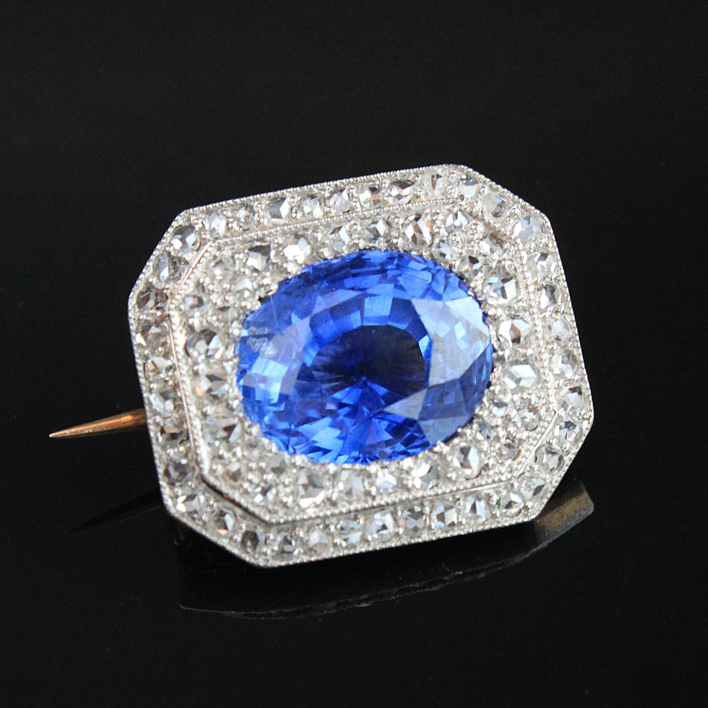 An Edwardian sapphire and diamond brooch in platinum and yellow gold, ca. 1910s. The central sapphire weighs approximately 9 carats and is a natural sapphire, not heated, and of Ceylon origin. It is surrounded by a double cluster of multiple rose