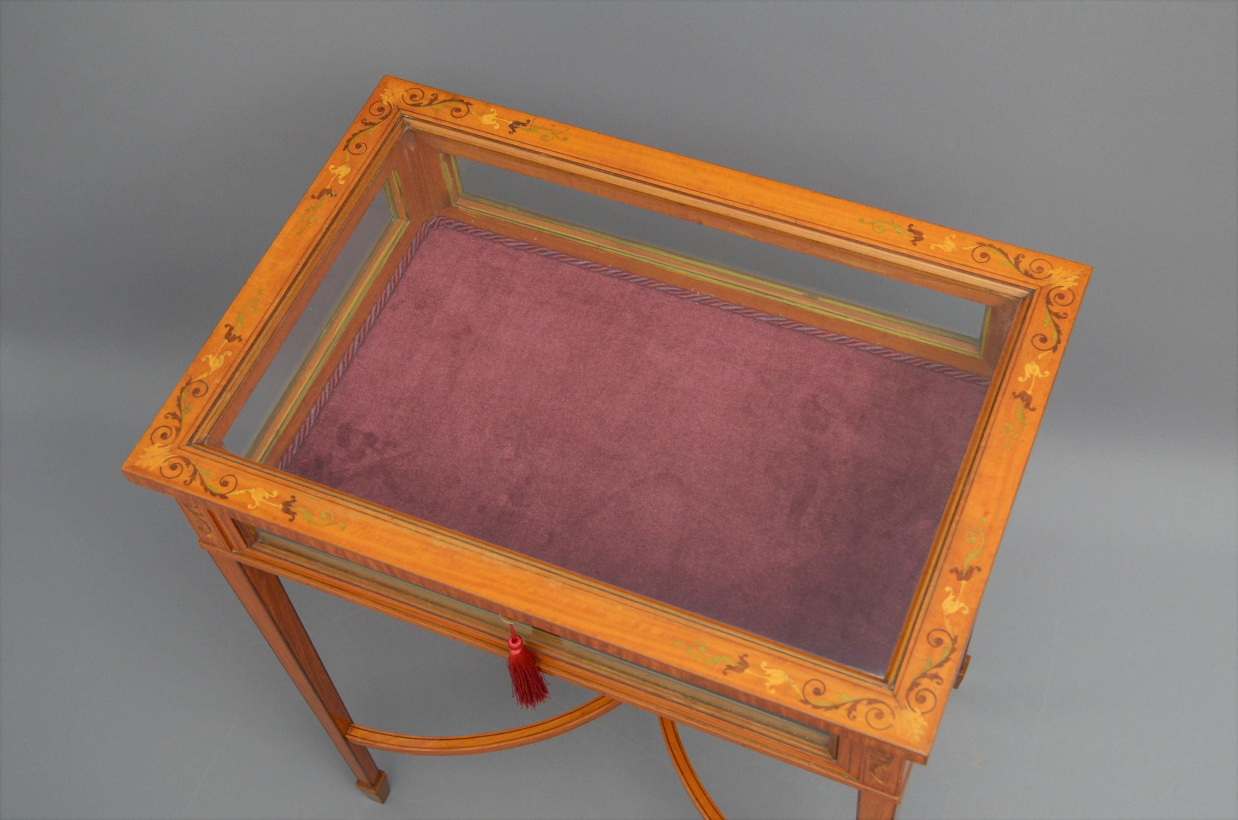 Sn5025, fine quality and very elegant Edwardian display table in satinwood, having floral inlaid hinged top with original working lock and a key, enclosing red velvet interior above four glazed sides flanked by scroll inlaid panels, standing on