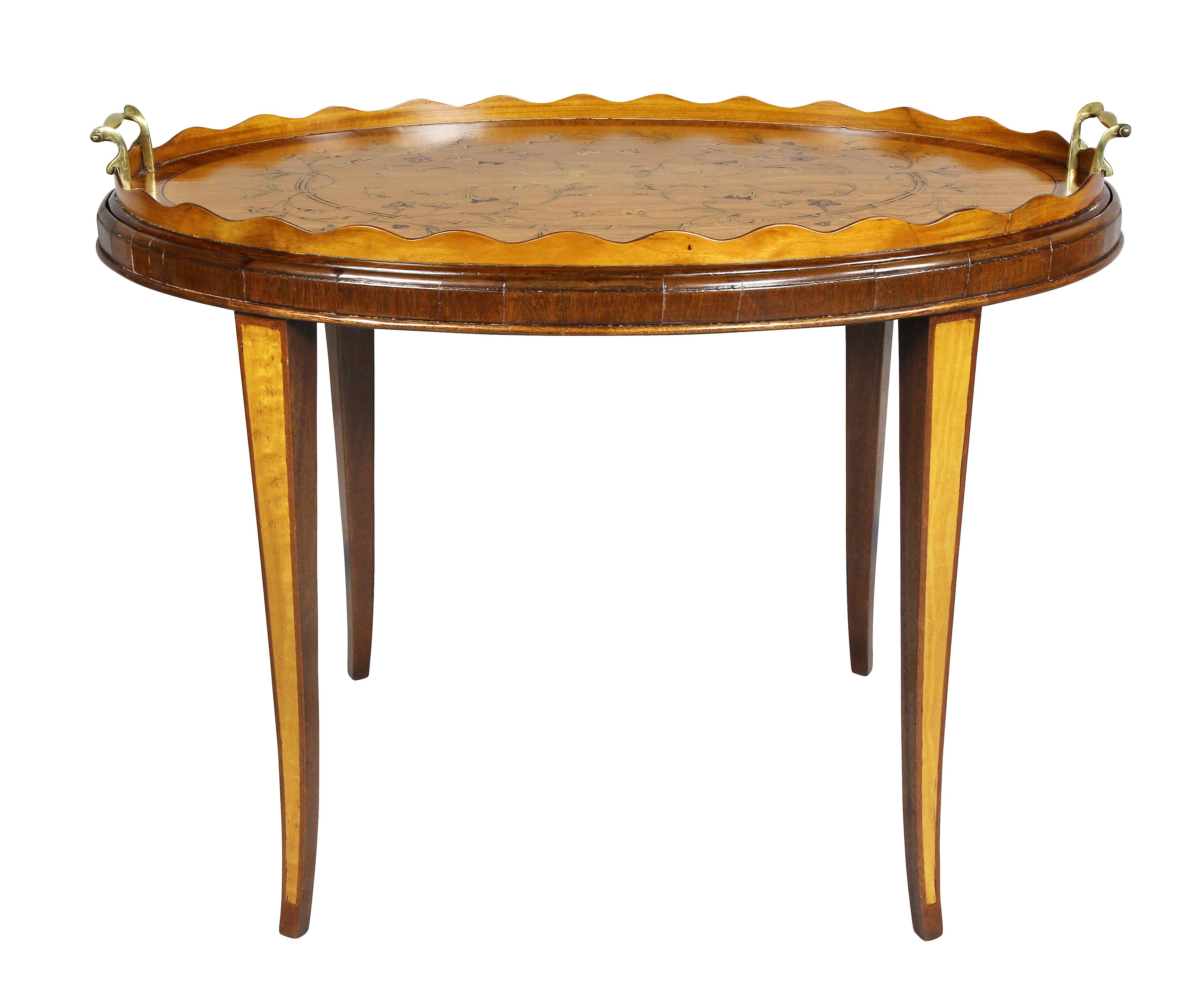 Oval with serrated gallery and rosewood banding outside a floral and leaf inlaid field, brass handles, raised on a later base with saber legs.