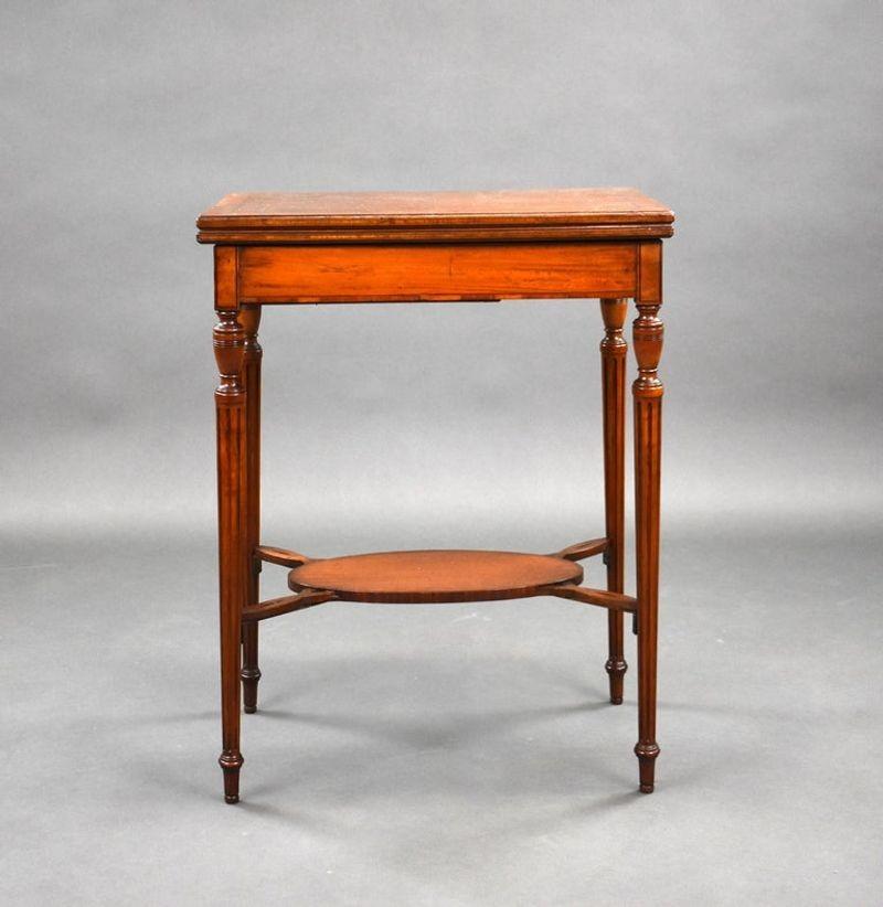 Edwardian antique satinwood card table. The table top swivels and opens to reveal a green baize and
stands on an elegant base with turned tapered legs.