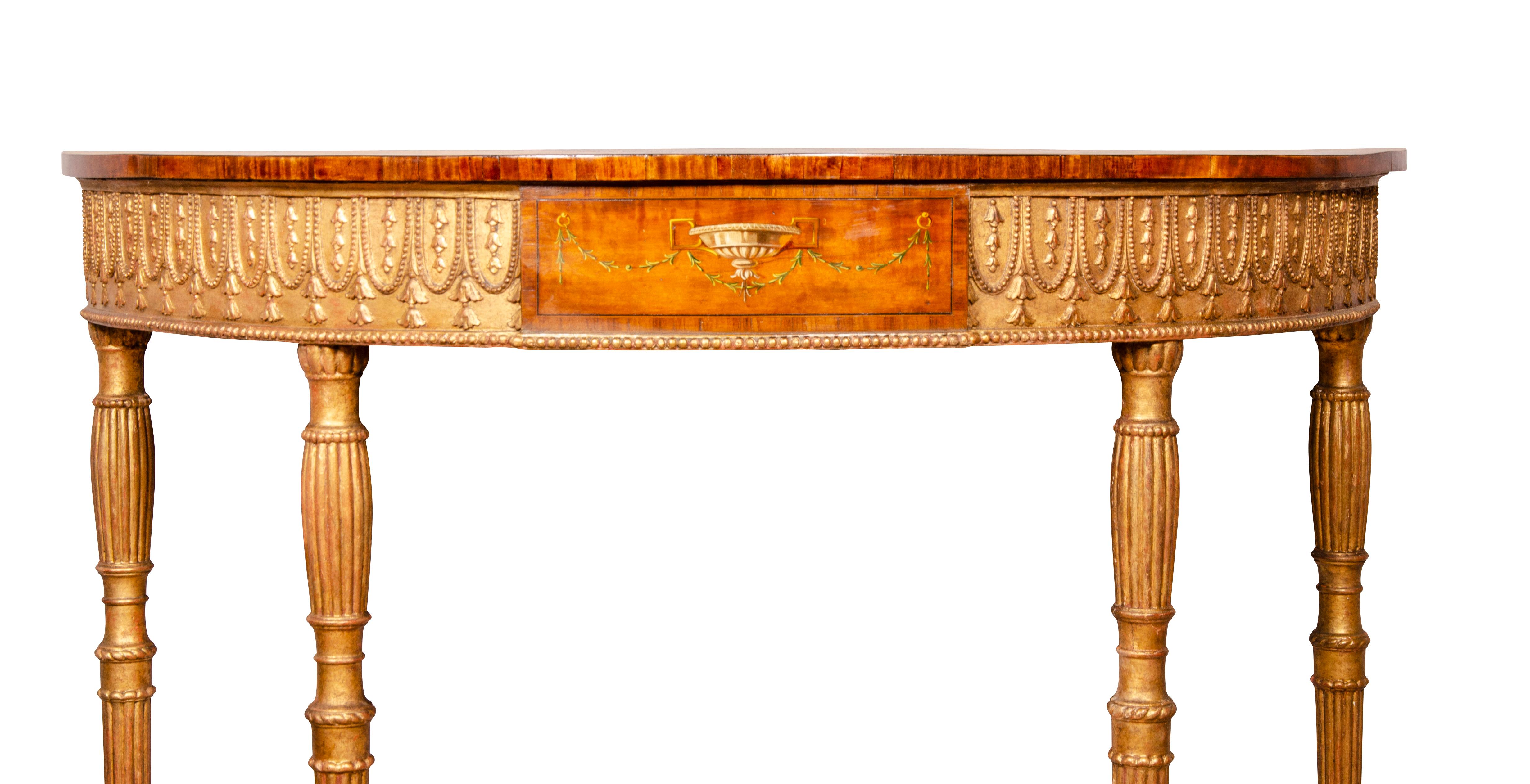 In the style of Robert Adam. Very fine quality with demilune top painted with classical scenes and floral garlands over a frieze with central painted panel and flanked by gilt wood lambrequin decoration raised on circular tapered reeded legs.