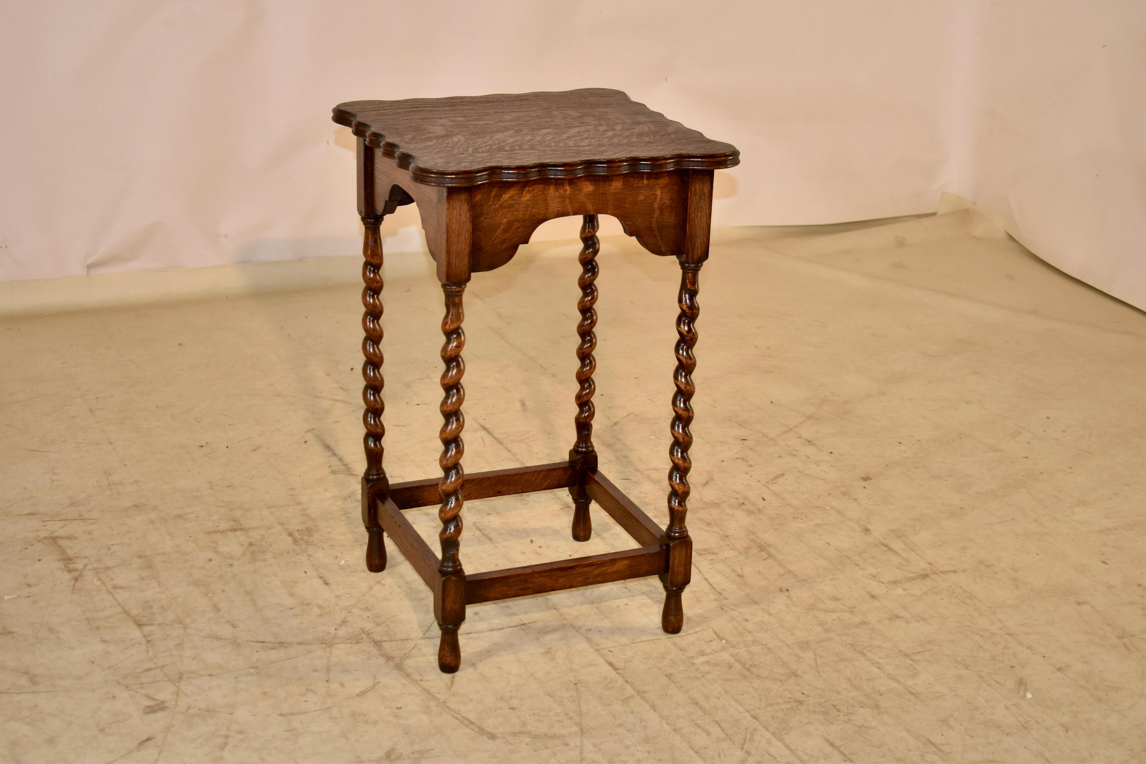 Circa 1900 English oak side table with a lovely scalloped top and molded edges.  The top follows down to a scalloped apron as well, and is supported on hand turned barley twist legs, joined by simple stretchers and raised on hand turned feet.