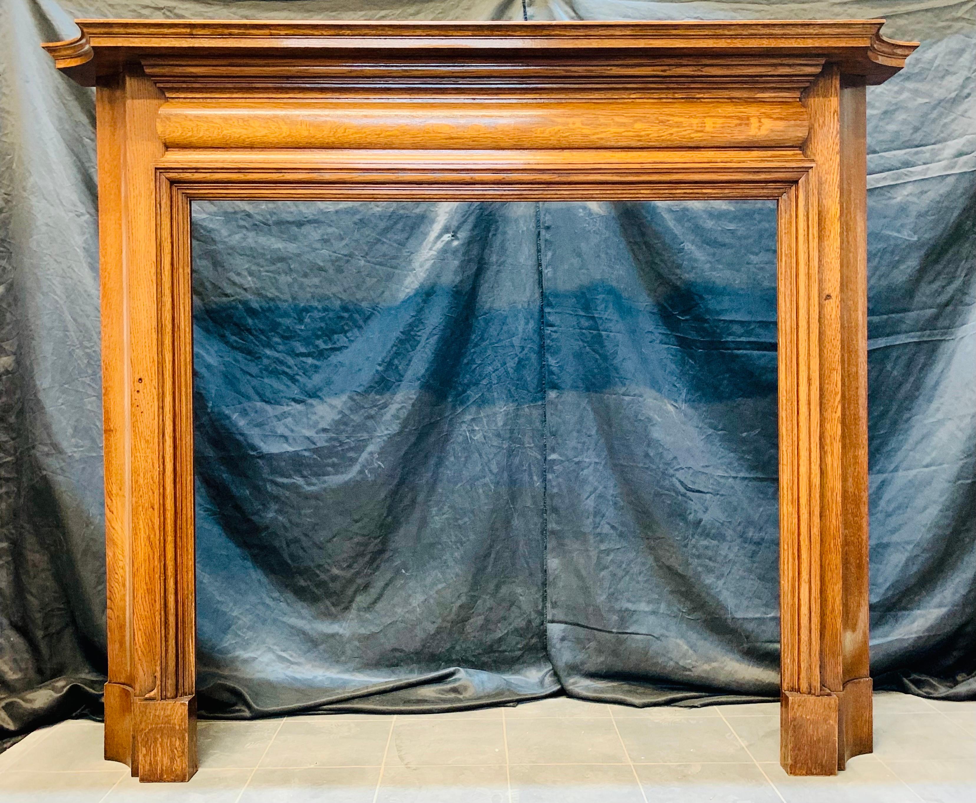 A versatile Edwardian Scottish Oak Fireplace Surround displaying a wonderful honey colour. A  generous moulded top shelf with a secondary shelf underscore this is shaped to overhang the attractive scalloped tall jambs. The frieze with a raised