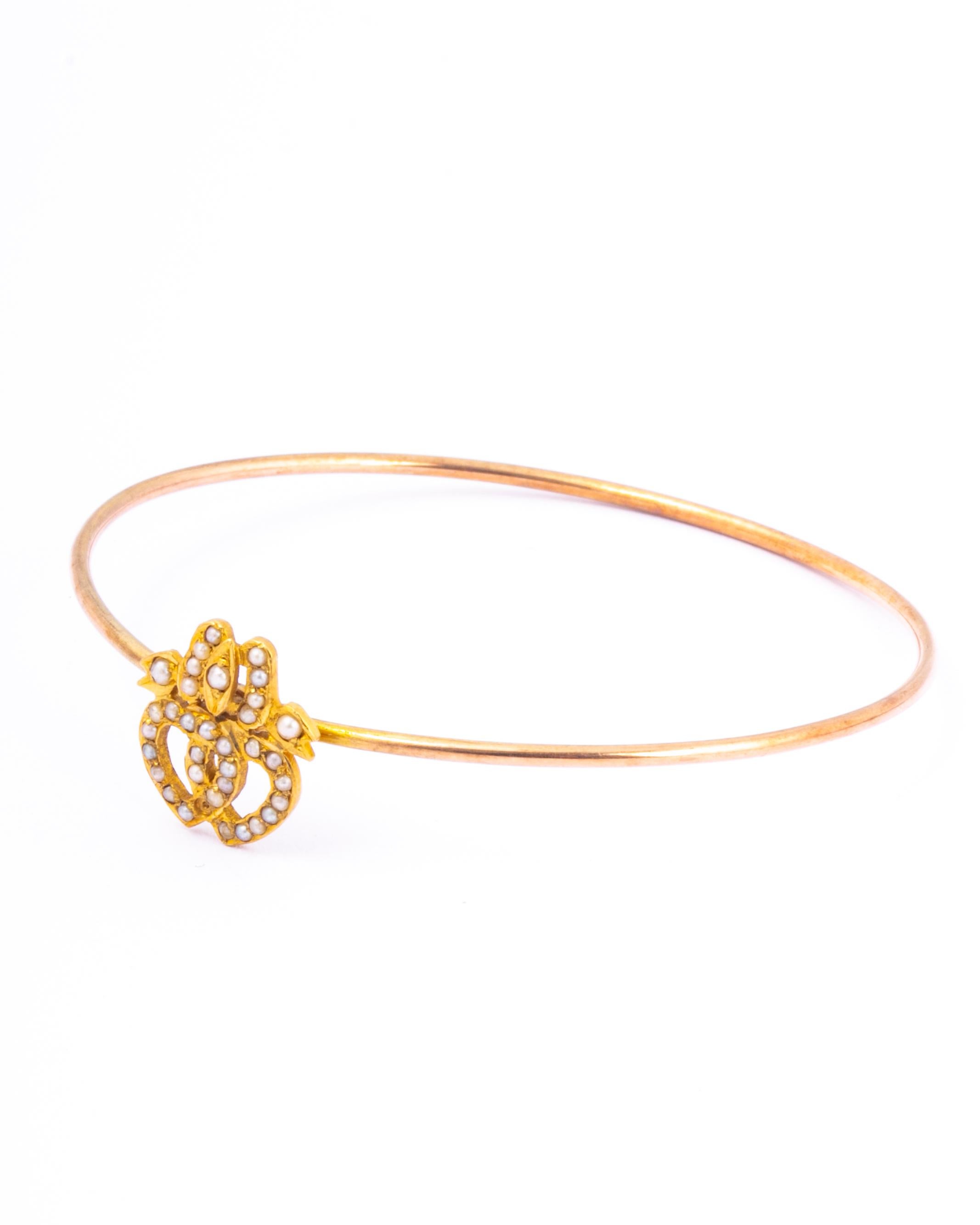 The 9 carat gold is bright and glossy and creates a classic style bangle. It fastens using a hook which hugs the double hearts. The hearts have seed pearls all the way around them with a bow above. 

Inner Diameter: 5.6cm
 
Weight: 5.35g

