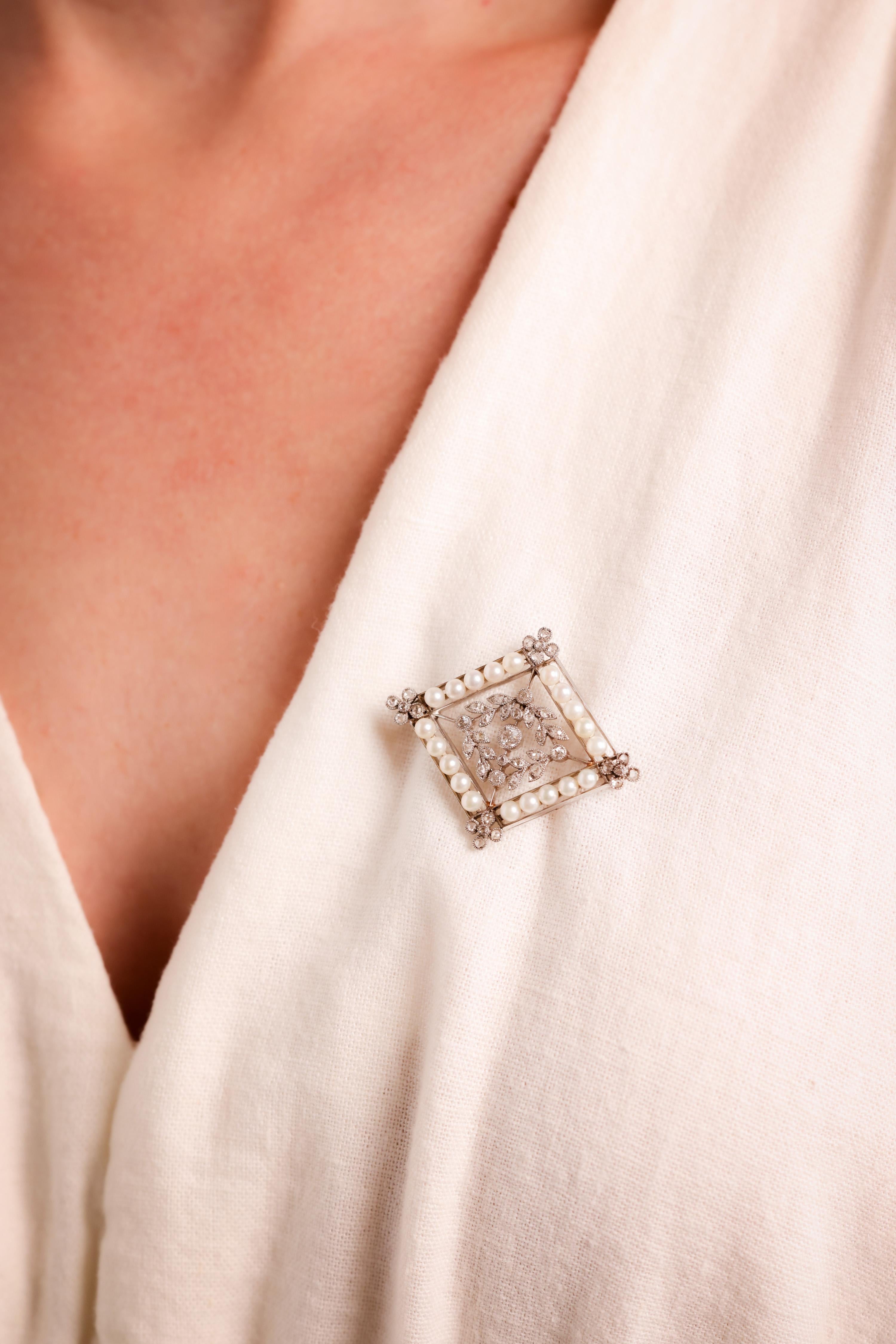 Center Stone: 20 Seed Pearls
Size: 2.86mm
Accent Stone: 42 Diamonds
Cut: Old European, Rose
Weight: Approximately 0.7 Carats
Color: I
Clarity: SI
Metal: Platinum
Era: Edwardian
Circa: 1910s
Hallmarks: Numbered 
Size: 1 3/8 x 1 5/8 inches 
Gram