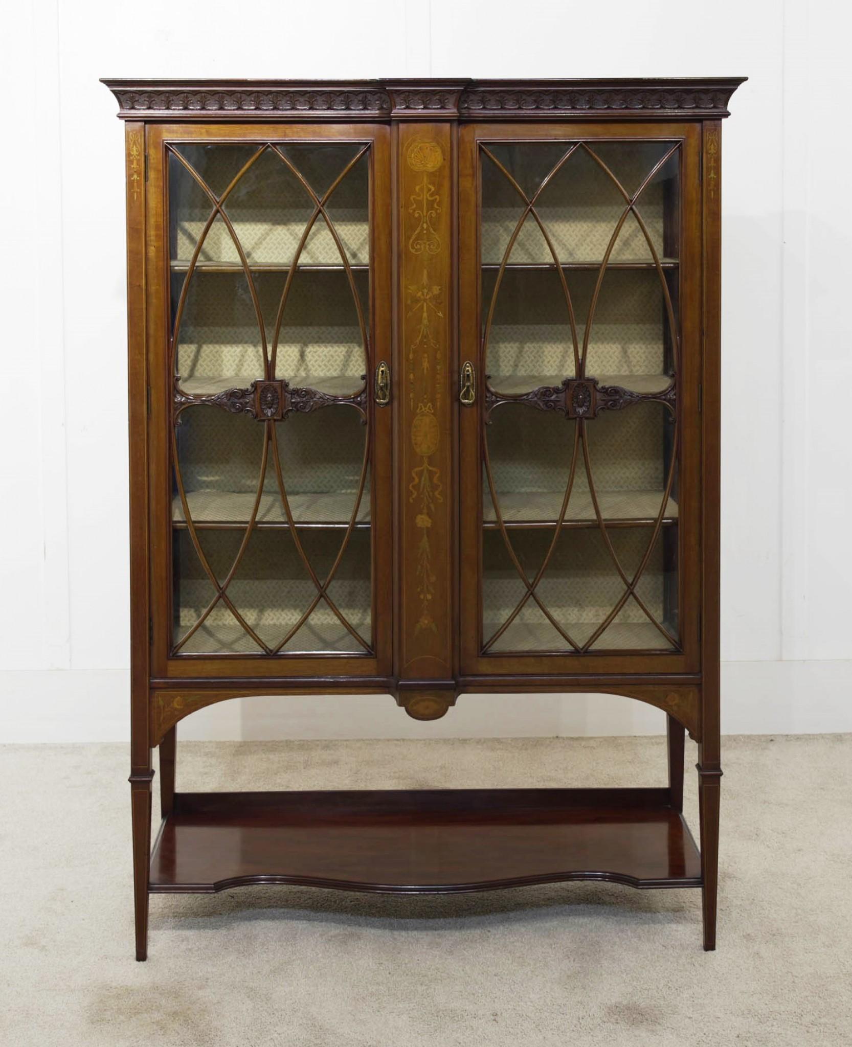 You are viewing a gorgeous Edwardian display cabinet in the Sheraton style
Crafted from mahogany with satinwood for the inlay designs including shells, garlands and other Sheraton motifs
Two glazed doors open out to reveal interior storage
