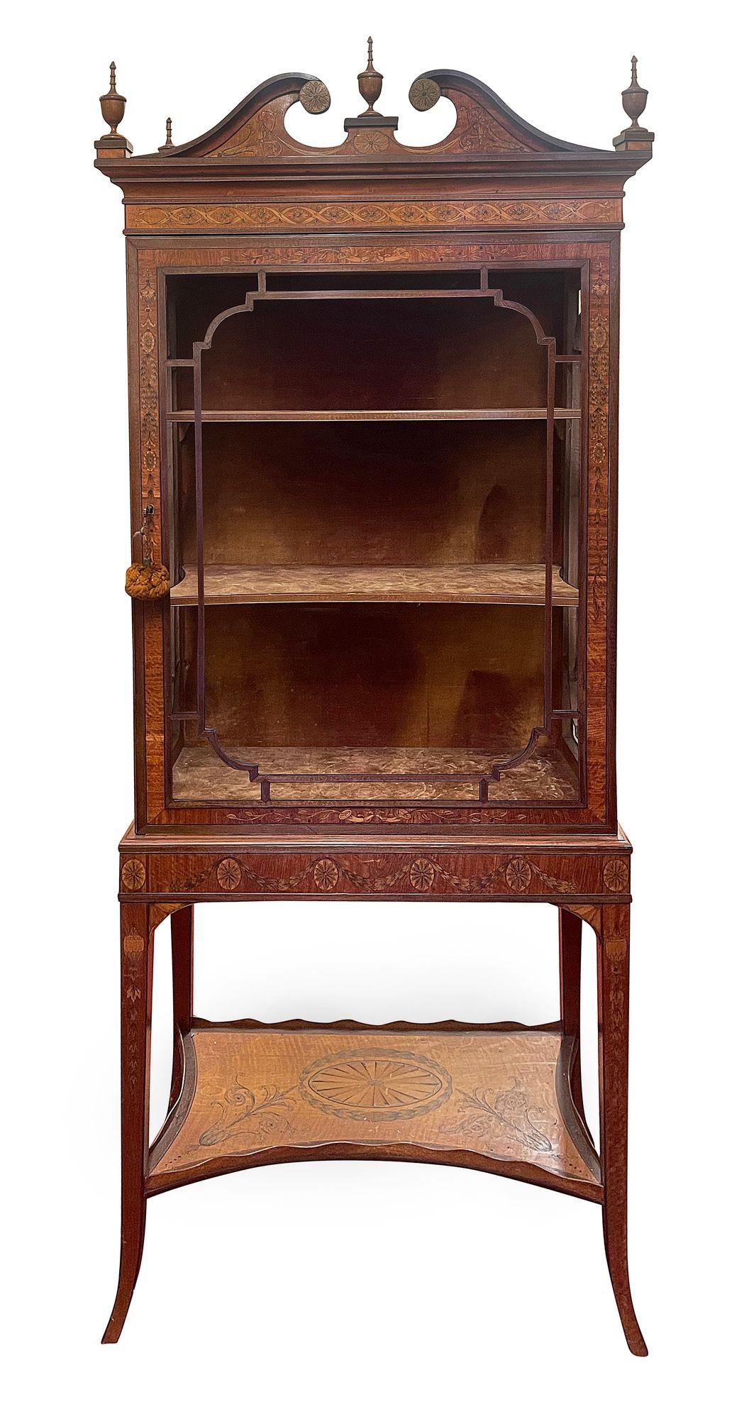 This fine quality Edwardian period display cabinet showcases the elegance of the Sheraton style, crafted from rich mahogany and adorned with intricate boxwood inlays. The cabinet features a beautifully swan neck pediment with decorative finials,