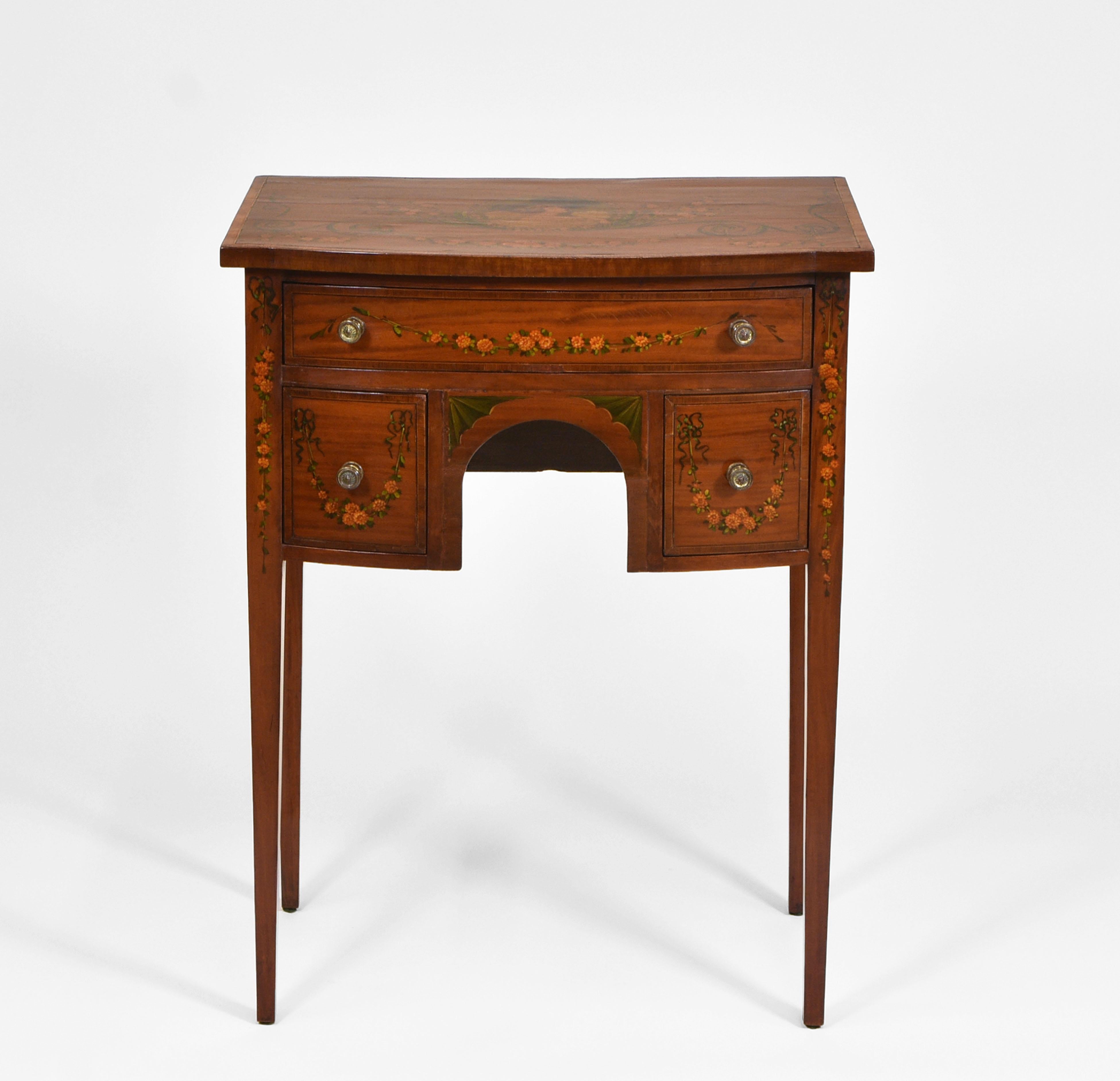 A lovely Edwardian Sheraton Revival painted satinwood side table. Circa 1900.

The table is of small proportions, veneered in satinwood with hand-painted classical decoration, including floral garlands, floral bouquets to the sides and a central