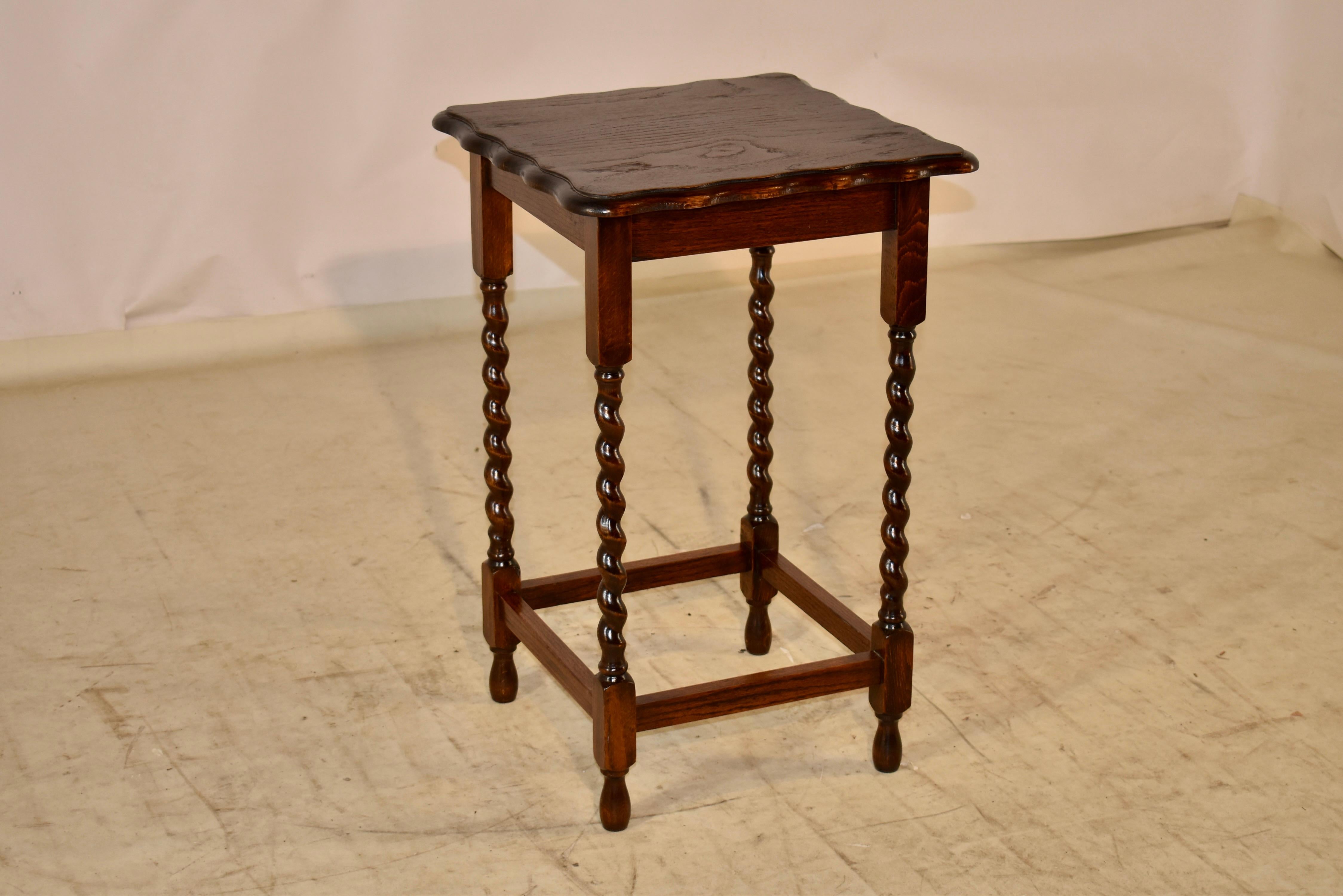 Edwardian oak side table from England with a scalloped and beveled edge around the top, which has fine figured wood. The apron is simple, and the table is supported on hand turned barley twist legs, joined by simple stretchers and raised on hand