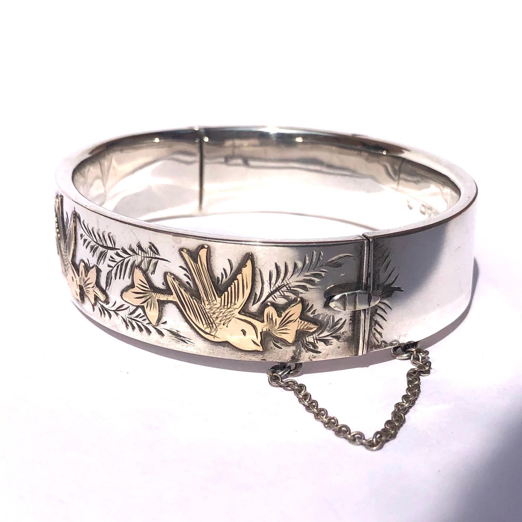 The exquisite detail on this bangle includes intricate engraving and gold overlay. The three beautiful gold birds are glossy and surrounded by leafy engraving. Made in Chester, England. 

Inner Diameter: 60mm
Bangle Width: 16mm 

Weight: 25g