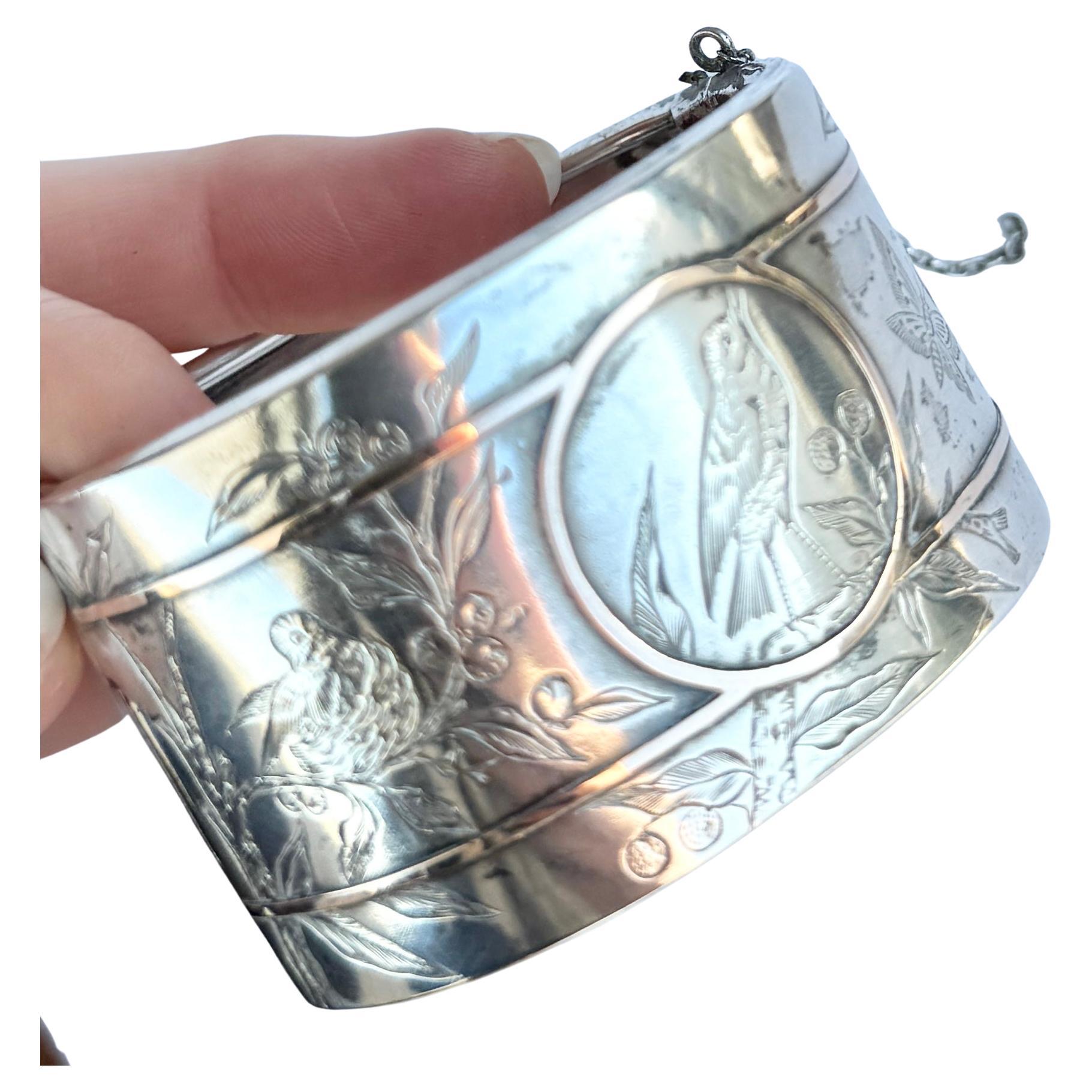 Sul pannello frontale di questo braccialetto è incisa in modo profondo e intricato una scena con uccelli, farfalle e piante. Anche questo braccialetto presenta dei dettagli in oro rosa. 

Diametro interno (dalla cerniera alla chiusura): 5.3