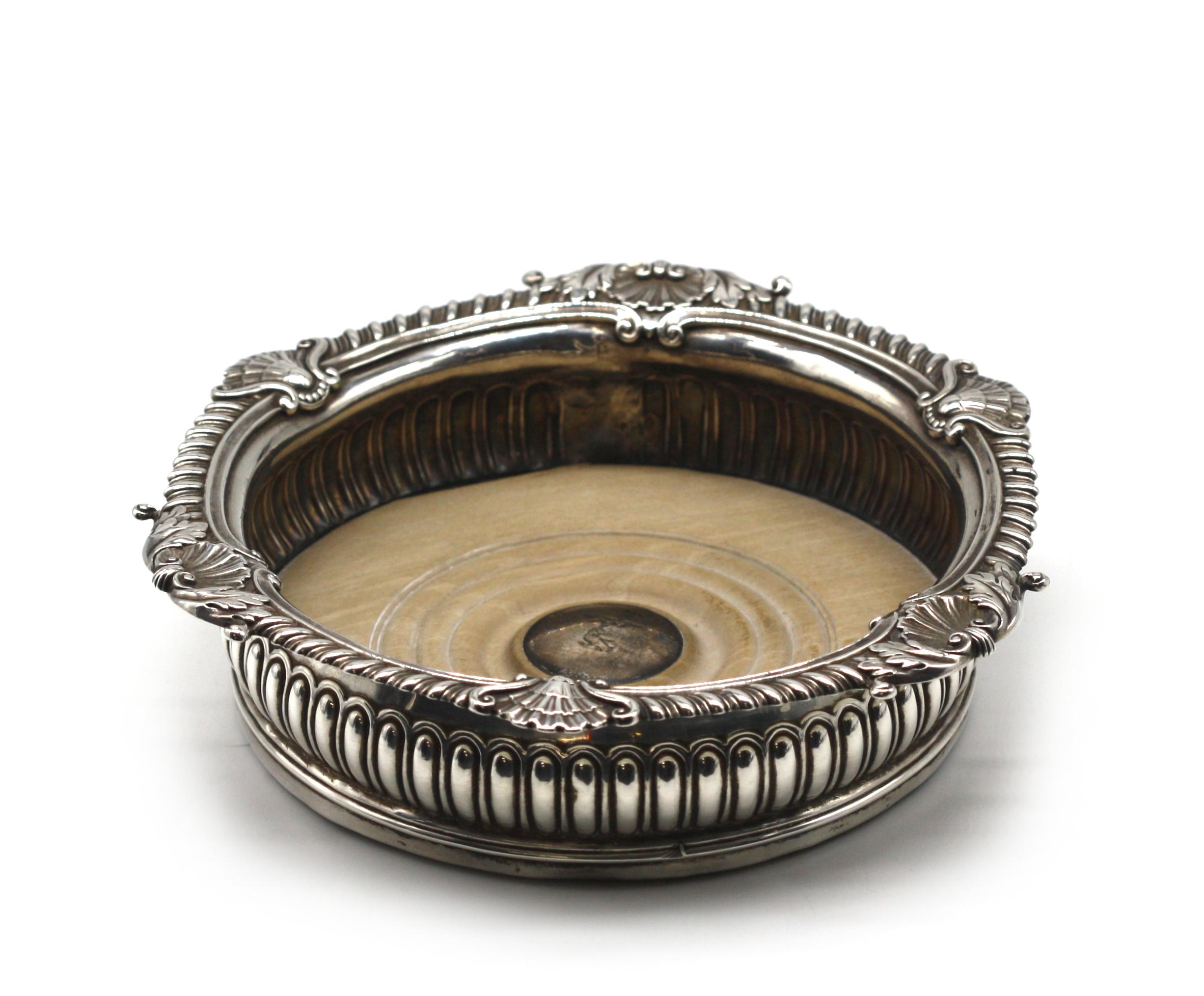 
Edwardian Silver and Treen Wine Coaster
1910, London hallmarks. Circular chased with gadroons and shells.
Height 2.75 in., Diameter 7 in.