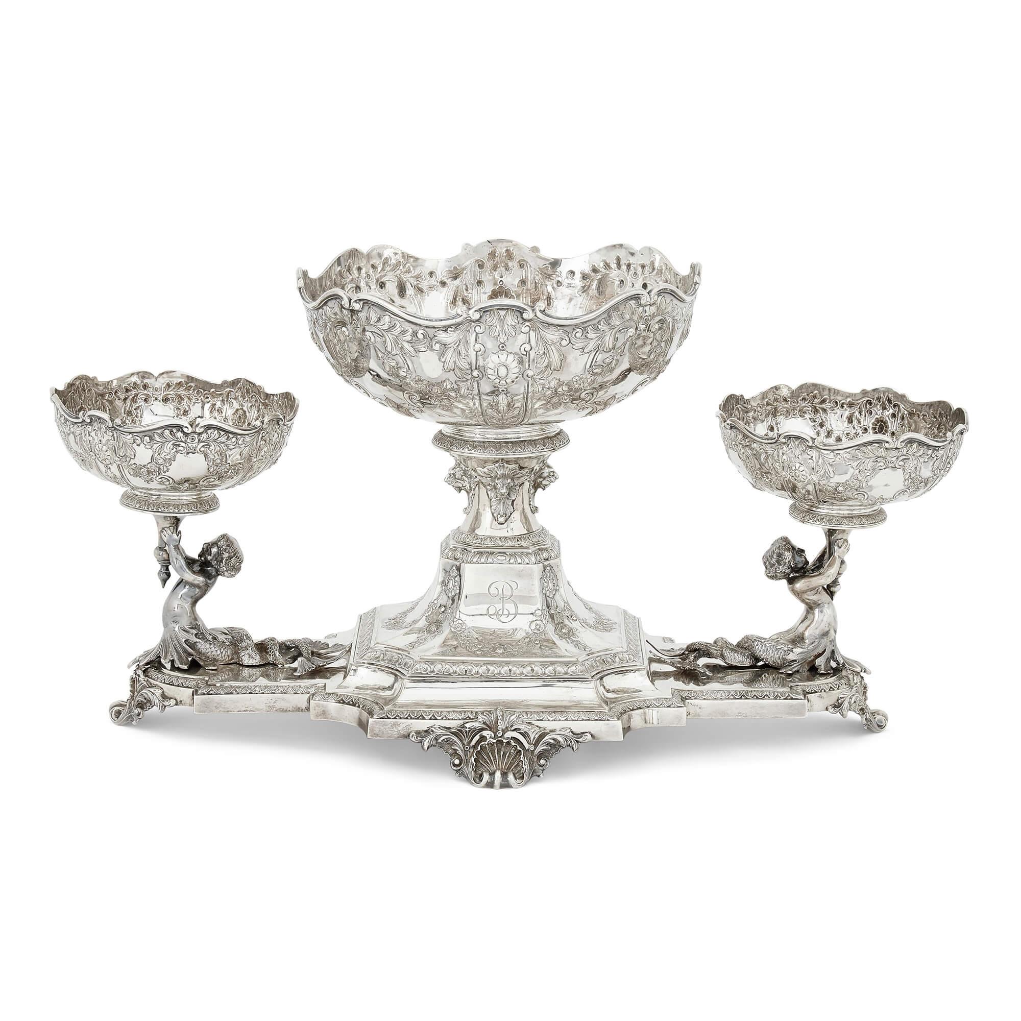 Edwardian silver centrepiece suite by Horace Woodward & Co. London
English, 1905
Epergne: Height 27cm, width 45cm, depth 26cm
Smaller comports: Height 13cm, diameter 14cm

This ornate centrepiece garniture is comprised of five pieces: a central