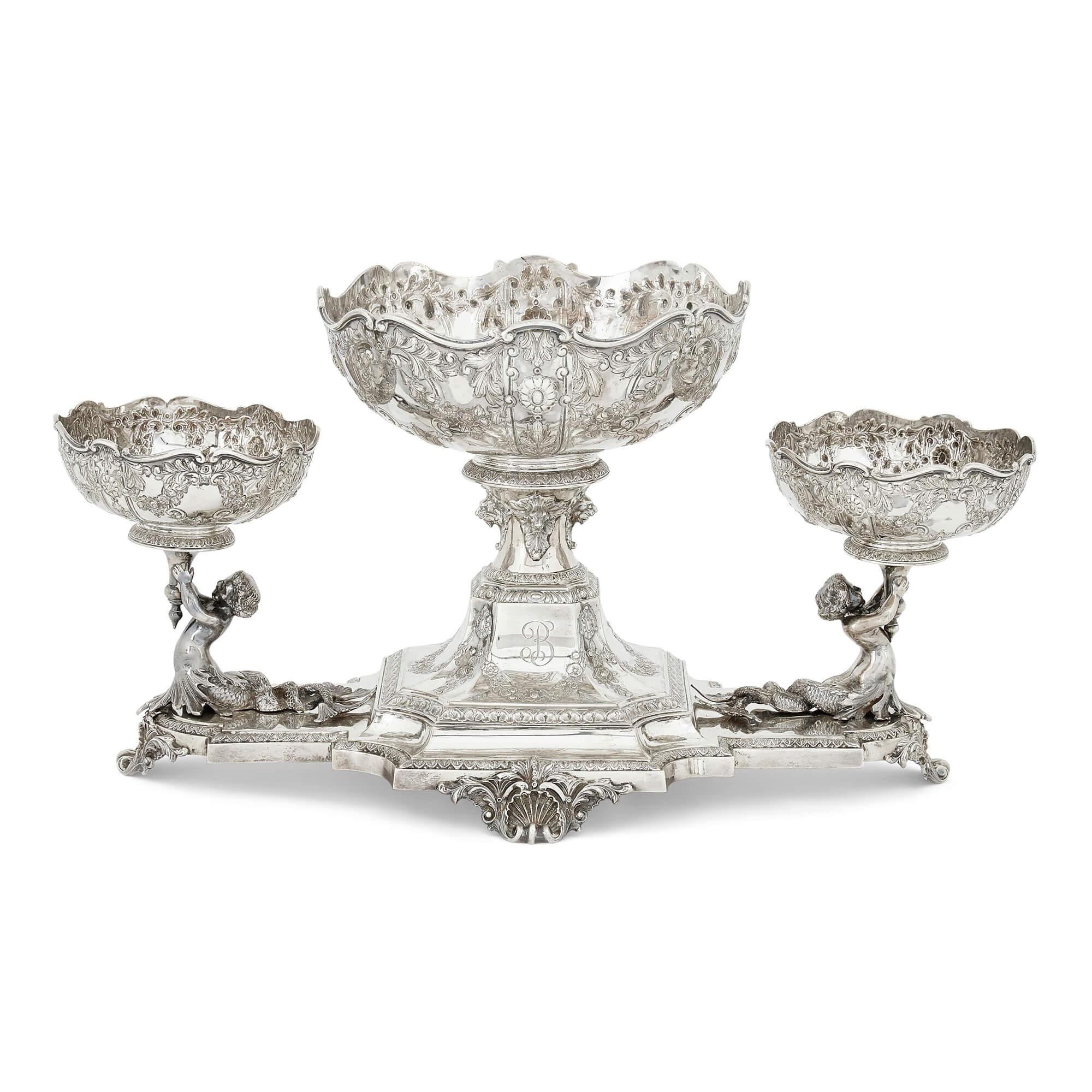 Conjunto de centro de mesa eduardiano de plata de Horace Woodward & Co. Londres
Inglés, 1905
Epergne: Altura 27 cm, anchura 45 cm, profundidad 26 cm
Comportamientos más pequeños: Altura 13 cm, diámetro 14 cm

Esta ornamentada guarnición de